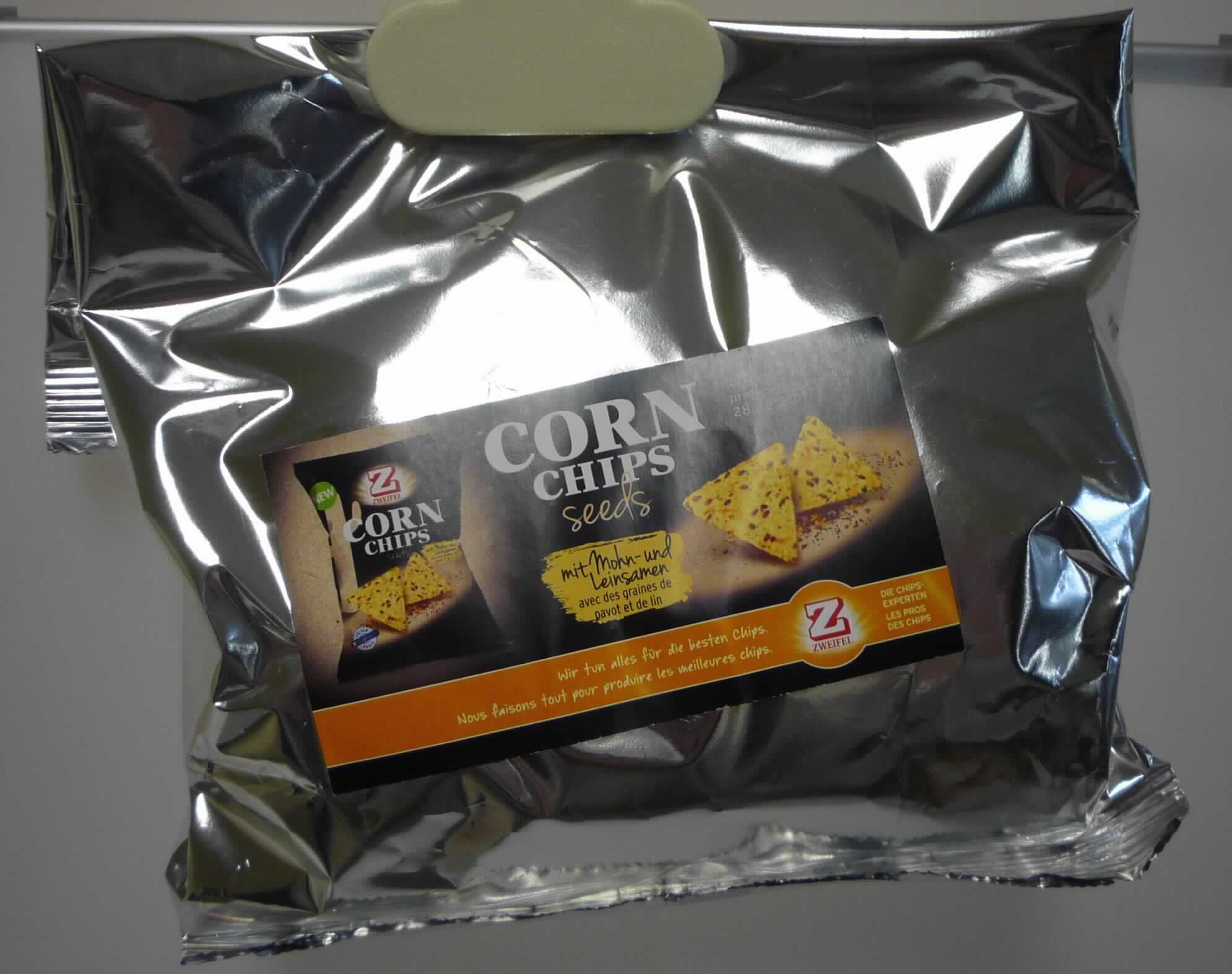 Corn Chips Multiseed 125 g

Antragsangaben:
Snack aus Mais mit Reis, Leinsamen und Mohnsamen;

Beschaffenheit des vorgelegten Warenmusters:
Goldgelb frittiertes Knabbergebäck in Form von dreieckigen (Kantenlänge ca. 5 cm), leicht aufgeblähten Tortilla-
Chips, die mit hellen und dunklen Leinsamen und kleinen schwarzen Mohnsamen durchsetzt sind. Geschmack 
nach frittierten Maischips mit Leinsamen, leicht salzig; als Warenmuster verpackt in etikettiertem alubeschichtetem 
Folienbeutel (Dummyverpackung). Die nachträglich vorgelegte Druckvorlage für die Original-Verpackungsfolie 
enthält den Markennamen (siehe Feld 8), mehrsprachige Angaben zum Erzeugnis ("Mais Chips mit Reis, 
Leinsamen und Mohnsamen"), zum Nenninhalt (125 g), zu den Zutaten und die GTIN (siehe jeweils Feld 8).

Stärke/Glucose*: 50 bis weniger als 75 GHT 
Saccharose/Invertzucker/Isoglucose**: weniger als 5 GHT 
Milchfett***: nicht enthalten 
Milchprotein***: nicht enthalten 

*  : festgestellt gemäß VO (EG) 900/2008, VO (EU) 118/2010
** : festgestellt gemäß VO (EG) 900/2008 
***: nach der Zutatenliste

Backware, expandiertes Erzeugnis, gesalzen oder aromatisiert