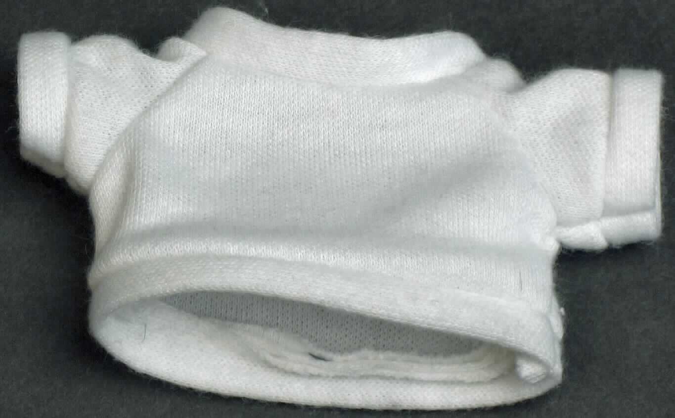 Es handelt sich um ein ca. 5 x 9 cm (HxB; Breite mit Ärmeln) großes, weißes T-Shirt aus Spinnstoff mit einem runden Halsausschnitt und kurzen Ärmeln. Der Kragenbereich, die Ärmelenden und der gerade, untere Rand des Shirts sind mit einem Bund ausgestattet.

Das T-Shirt ist aufgrund der Gestaltung erkennbar hauptsächlich als Zubehör für Puppen bestimmt. Eine mögliche anderweitige Verwendung steht der Einreihung nicht entgegen. 

Die Ware dient der spielerischen Unterhaltung von Kindern mit Puppen.

Das Erzeugnis ist als "Zubehör für Puppen, nur Nachbildungen von Menschen darstellend" einzureihen.