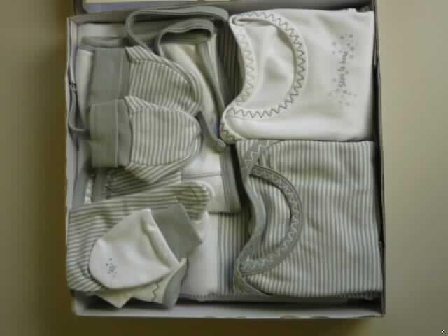 Achtteilige Zusammenstellung für Kleinkinder, bestehend aus einteiliger Unterwäsche
(Sortiment mit zwei Langarmbodies), einem Paar Handschuhe, einem Paar Socken (sog.
Schuhe), einem Halstuch für Kleinkinder (sog. Dreieckstuch; zweiteilig), einer Mütze, einem
Lätzchen und einer Decke, sog. Geschenkbox aus 8 verschiedenen Artikeln (Art. 19904),
Größe 62, siehe Fotos,
- in einer gemeinsamen Umschließung aus Pappe und Kunststofffolie für den Einzelverkauf  
  aufgemacht,
- keine Warenzusammenstellung im Sinne der AV 3 b), da u.a. die Decke und die anderen
  Bestandteile nicht der Befriedigung eines speziellen Bedarfs dienen, somit getrennte
  Einreihung aller Bestandteile, 
- alle Bestandteile aus Gewirken aus laut Antrag 100% Baumwolle,
- Handschuhe (Art. 96191):
-- in Form von Fausthandschuhen ohne ausgeformten Daumen,
-- am Handgelenk mit einem doppelt gearbeiteten, umgeschlagenen Stulpen,
-- aufgrund der Form (ohne ausgearbeiteten Daumen) und der Größe (Handlänge: 8,5 cm) 
   erkennbar Bekleidungszubehör für Kleinkinder.