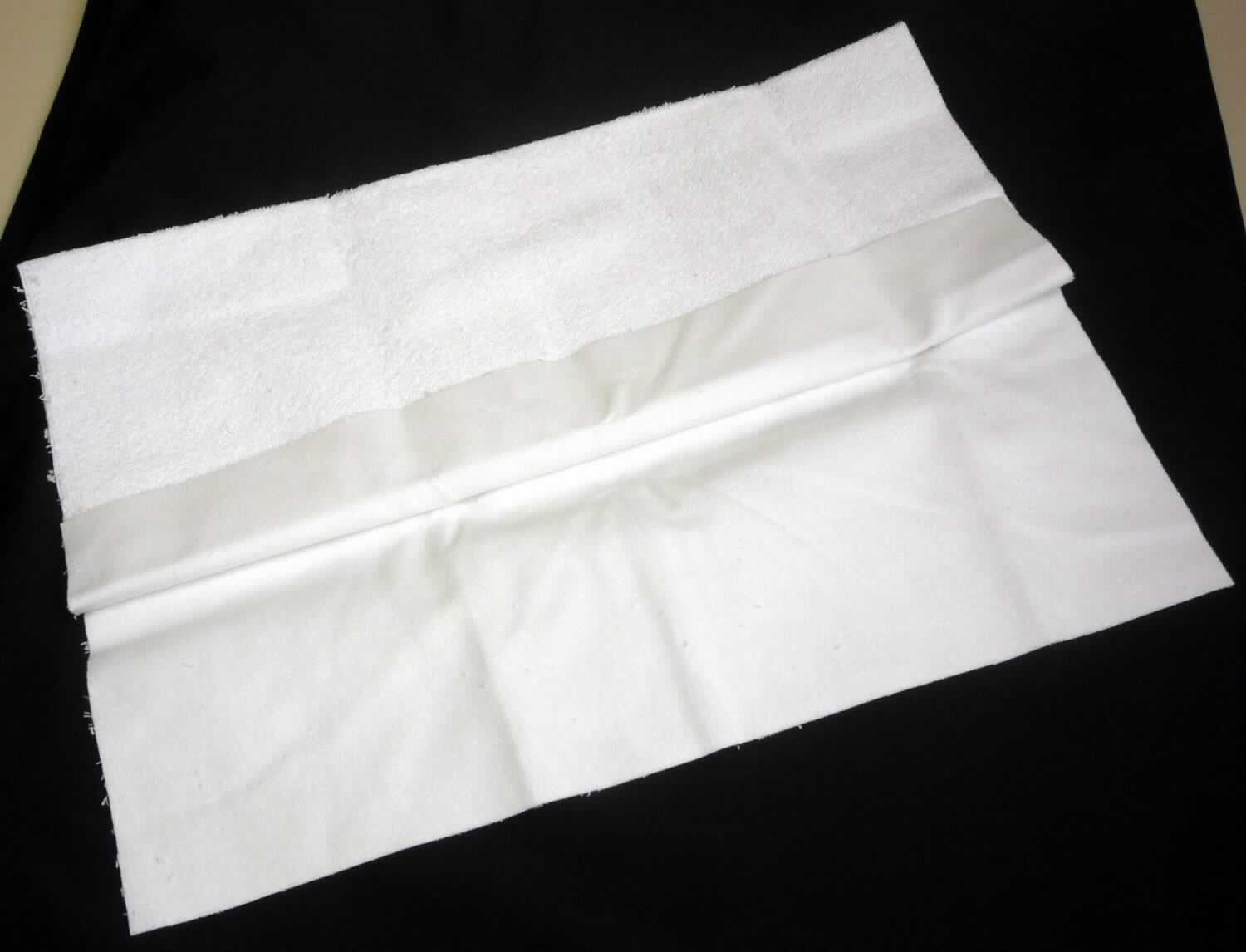 Textillaminat, sog. Wasserdichte Betteinlagen, Foto siehe Anlage,
- rechteckig zugeschnitten (somit nicht konfoktioniert), in den Abmessungen (L x B): 50 cm x 40 cm,
- aus drei mit ihrer ganzen Fläche aufeinander liegenden und so miteinander durch Kleben verbundenen Lagen: 
-- mit einer Außenlage aus Schlingengewirken aus verschiedenen Spinnstoffen, mit einer Schlingenoberfläche aus 
   laut Antrag Baumwolle, 
-- mit einer Zwischenlage aus einer Folie aus laut Antrag Kunststoff,
-- einer weiteren Außenlage aus einseitig (Außenseite) gerauten Geweben aus laut Antrag Baumwolle, 
- dient als Nässeschutz für Kindermatratzen,
- im Hinblick auf den Umfang und und die Bedeutung in Bezug auf die Verwendung sind die beiden 
  Flächenerzeugnisse (Gewirke/Gewebe) als gleichbedeutend zu betrachten, im Hinblick auf den Wert bestimmt 
  jedoch das Schlingengewirke den Charakter der Ware.

"Schlingengewirke, aus Baumwolle"
