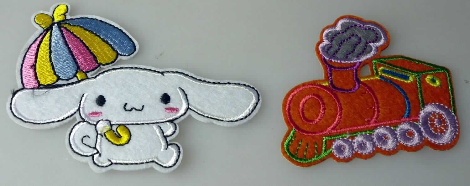 Stickerei als Motiv, sog. ALDI Hofer "Kindermotive", Foto siehe Anlage,
- in unterschiedlichen Motiven, veranschaulicht durch zwei Muster: ein stilisiertes Tier mit Schirm (ca. 9 cm x 7 cm)
  und eine Lok (ca. 6,5 cm x 5,7 cm) darstellend,
- auf einem Stickgrund aus augenscheinlich Vliesstoff mit Stickgarnen bestickt, beide aus laut Antrag Polyester 
  (synthetische Chemiefasern),
- auf der Rückseite mit einem klarsichtigen Kleber ausgestattet,
- keine Ätzstickerei oder Stickerei mit herausgeschnittenem Grund,
- laut Antrag mit einem Wert von mehr als 17,50 EUR je kg Eigengewicht,
- ohne Hinweise auf Handarbeit.

"Stickerei als Motiv, andere als Ätzstickereien und Stickereien mit herausgeschnittenem Grund, aus Chemiefasern, 
 mit einem Wert von mehr als 17,50 EUR je kg Eigengewicht, nicht handgearbeitet"