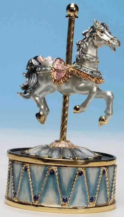Sog. Spieluhr "Blaues Karussellpferd", Art. Nr. 25059, siehe Foto.
Es handelt sich um eine Spieldose aus emailliertem Metall, die ein Karussellpferd an einer Stange auf einer Trommel darstellt (Höhe: 110mm). Nach dem Aufziehen des Mechanismus dreht sich das Pferd zur Melodie "Eine kleine Nachtmusik".

Diese Ware ist als "Spieldose" einzureihen.