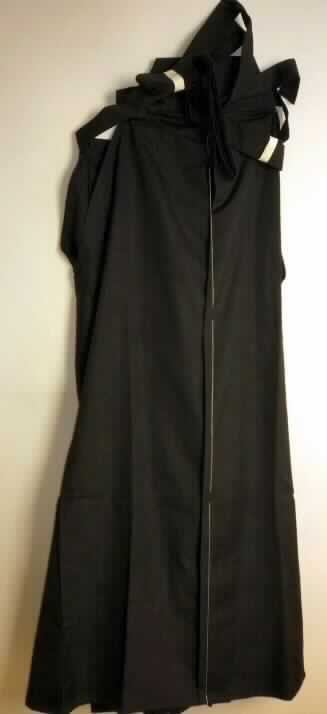 Hosenrock, sog. Hakama, japanische Größe 28, Foto siehe Anlage,
- aus ca. 0,4 mm dicken, einfarbigen Geweben aus laut Antrag 65 % Polyester (synthetische 
  Chemiefasern) und 35 % Baumwolle,
- in der Taille abschließend und bis zu den Knöcheln reichend,
- an den Seiten, von der Taille abwärts mit einer ca. 31 cm langen, V-förmigen Öffnung, 
- am Vorderteil mit einem angesetzten, doppelt gearbeiteten, ca. 3,7 cm breiten Bund, der in bis zu 163 cm 
  lange Bindebänder übergeht, 
- im unteren Rückenbereich mit einer angesetzten, trapezförmigen, ca. 9,5 cm hohen und bis zu 25 cm breiten, 
  vollständig mit Gewebezuschnitten überzogenen Platte aus Kunststoff (sog. koshi-ita) ausgestattet; 
  mit einem aufgenähten doppelt gearbeiteten, ca. 4 cm breiten Band, das in bis zu 79 cm lange Bindebänder 
  übergeht,
- die Bindebänder werden um die Taille geschlungen und verknotet, 
- ohne Öffnung und ohne Verschluss, ohne Hinweise auf den Trägerkreis (unisex),
- vorn mit mehreren, von der Taille bis zu den Hosenbeinenden reichenden, breiten Falten,
- mit sehr weiten, knöchellangen Hosenbeinen (Seitenlänge: 110 cm), die dem Kleidungsstück 
  aufgrund der Schnittform den optischen Eindruck eines Rocks und damit den Charakter eines 
  Hosenrocks verleihen (somit keine lange Hose), 
- an den Beinabschlüssen durch Umschlagen und Festnähen gesäumt.

"Hosenrock aus Geweben, für Frauen, aus synthetischen Chemiefasern, nicht im Batikverfahren handbedruckt"