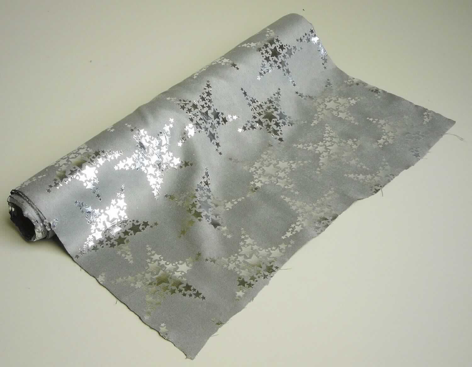 Gewebe, sog. Dekostoff mit Sterndesign, Foto siehe Anlage,
- als Meterware auf Rollen, laut Antrag mit einer Länge von 300 cm und einer Breite von 36 cm,
- aus einem geschmirgelten Gewebe,
- mit Farbe bedruckt,
- aus ungezwirnten, nicht hochfesten Garnen aus synthetischen Filamenten und synthetischen Mikro-Spinnfasern 
  (beide laut Antrag aus Polyester),
- mit einem Gesamtanteil an:
-- synthetischen Filamenten von ca. 60 GHT (damit keine Ware der Unterposition (HS) 5407 61),
-- synthetischen Spinnfasern von ca. 40 GHT,
- an den Längskanten lediglich heiß geschnitten.

"Gewebe aus Garnen aus synthetischen Filamenten, anderes als in den Unterpositionen 5407 10 bis 5407 84
 genannte, bedruckt"