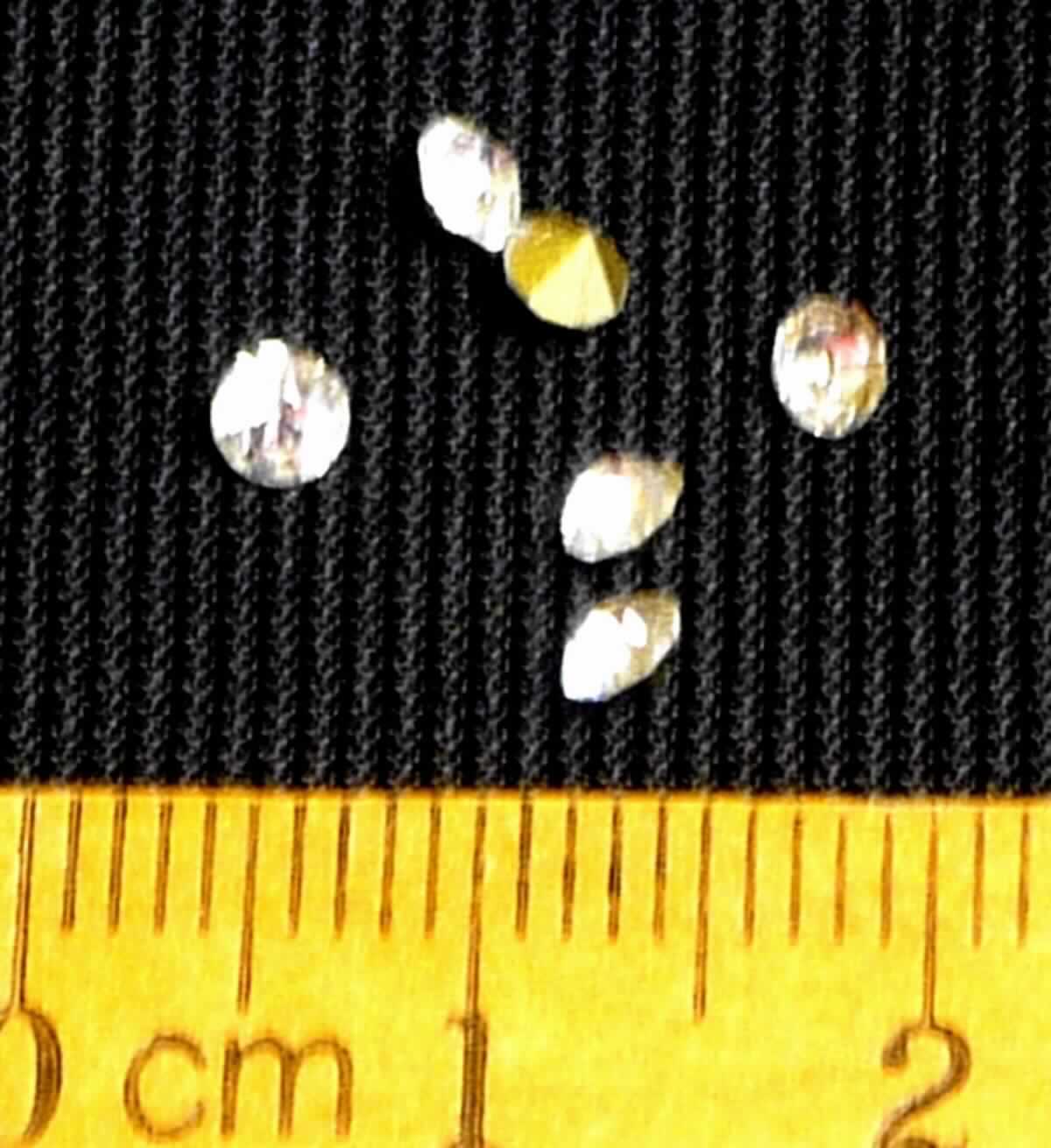 Nachahmungen von Edelsteinen, sog. Schmucksteine, Foto siehe Anlage,
- in Form von Diamant-Imitationen (Diamantschliff),
- aus gewöhnlichem, klarsichtigem Glas; laut Antrag geschliffen und mechanisch poliert,
- auf der Unterseite messingfarben bemalt,
- mit Durchmessern von ca. 3 mm.

"Nachahmungen von Edelsteinen, geschliffen und mechanisch poliert"