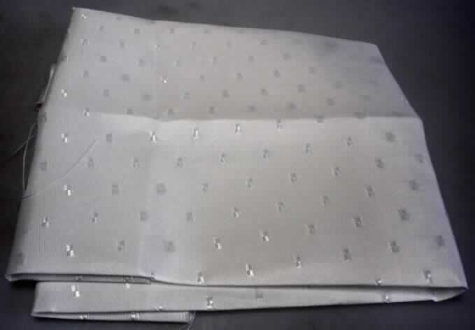 Jacquardgewebe, sog. Gewebe, texturiert Farbe weiß, Foto siehe Anlage,
- als Meterware; mit einer Breite von mehr als 30 cm,
- laut Untersuchungsergebnis:
-- aus ungezwirnten, nicht hochfesten Garnen aus nicht texturierten
   Polyester-Filamenten (synthetische Filamente),
-- in Musterbindung (geometrische Musterung),
-- weiß gefärbt (= gebleicht).

"Gewebe aus Garnen aus synthetischen Filamenten, anderes als in den Unterpositionen 5407 10 bis 5407 54 genannte, mit einem Anteil an nicht texturierten Polyester-Filamenten von mehr als 85 GHT, gebleicht"