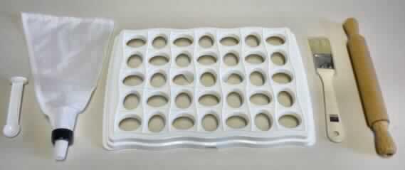 Bei dem durch ein Warenmuster veranschaulichten Artikel handelt es sich um eine Warenzusammenstellung in Aufmachung für den Einzelverkauf (Pappkarton mit Polybeutel) in Form eines so genannten 5-teilgen Ravioli-Sets aus Kunststoffen im Sinne der Anmerkung 1 zu Kapitel 39 bestehend aus:

- einem Raviolibrett mit einer Größe von ca. 30,00 x 20,50 x 2,00 cm und 35 vorgestanzten, 
  ovalen Aussparungen zum Formen der Ravioli (Position 3924),
- einem speziell gestalteten, ca. 9,30 cm langen Löffel mit einer runden Laffe und einem 
  ovalen Formstück am Ende des Stiels, passgenau für die Ausstanzungen des 
  Raviolibretts (Position 3924),
- einem ca. 29,00 cm großen Spritzbeutel aus Spinnstoffen (Position 6307)
- einem Backpinsel mit einer Länge von ca. 19,00 cm (Position 9603) und
- einem Teigroller aus Holz mit einer Länge von ca. 24,00 cm  (Position 4419).

Im Hinblick auf die Menge, die spezielle Gestaltung bzw. Beschaffenheit und dem Umfang bestimmen die Kunststoffartikel im Sinne der Position 3924 den Charakter der Warenzusammenstellung. 

Derartige Erzeugnisse werden zolltariflich als "Haushaltsartikel aus Kunststoffen für den Küchengebrauch" eingereiht.