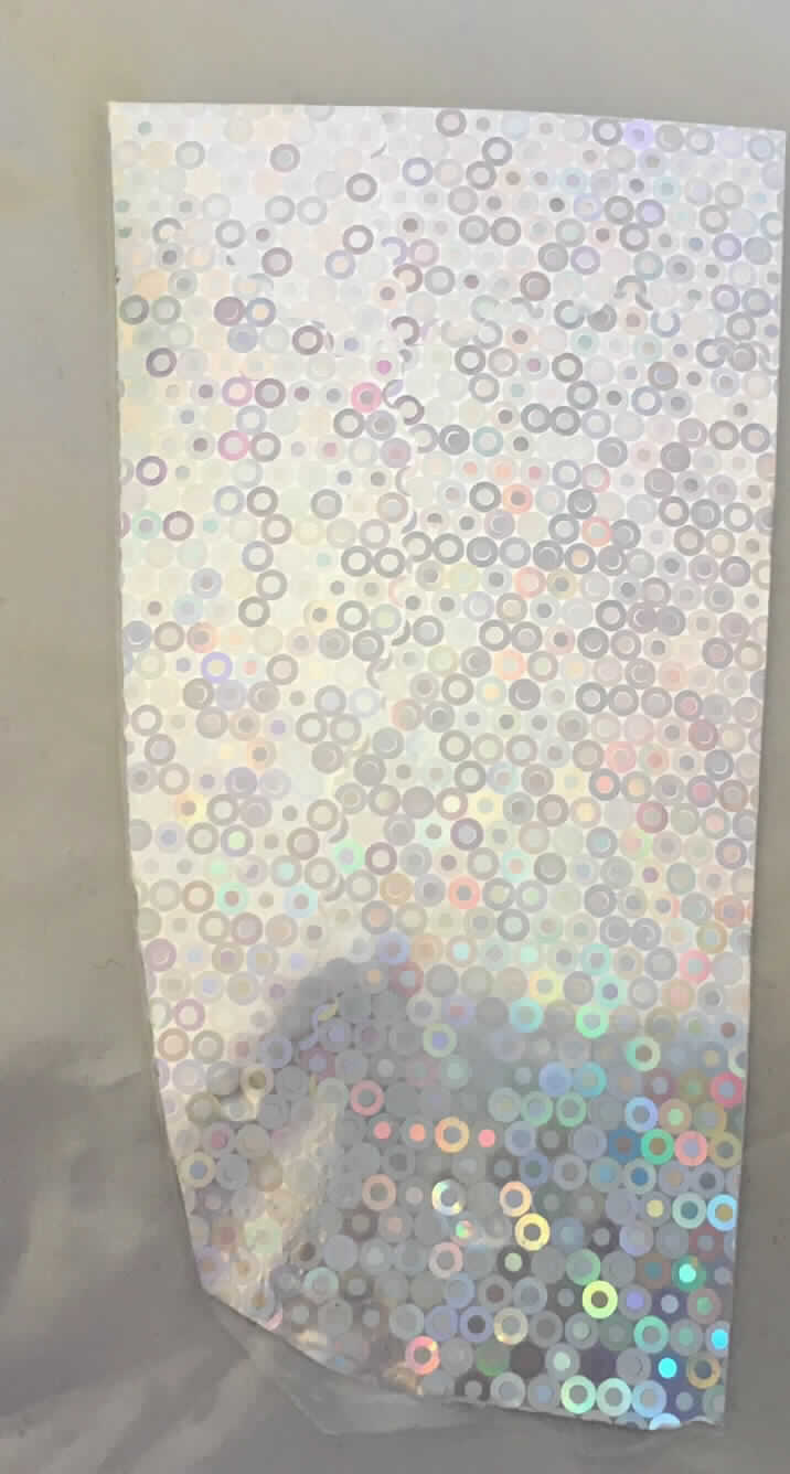 Nach dem zur Veranschaulichung vorgelegten Probenzuschnitt und den ergänzenden Angaben der Antragstellerin handelt es sich um eine Kunststofffolie als Trägerfilm, die einseitig mit einer Dekorschicht (holografisches Kreismuster) bedruckt und mit einer Heißklebeschicht versehen ist. Durch Wärme und Druck lässt sich die Dekorschicht auf einen anderen Träger (z. B. auf Kleidungsstücke) übertragen. Die Folie wird in Rollen mit einer Breite von 1 bis 100 cm eingeführt.

Abbildung siehe Anlage.

Derartige Waren gehören als "Abziehbilder aller Art, nicht verglasbar" zur Codenummer 4908 90 00 00 0 des Zolltarifs.