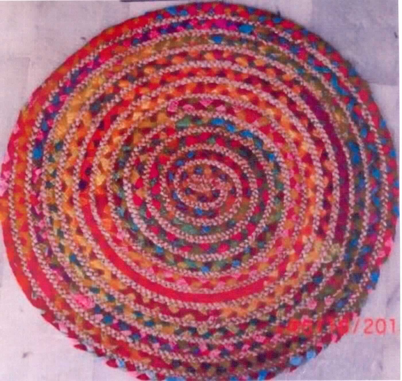 Teppich, Art. Selina, Foto siehe Anlage,
- rund, mit einem Durchmesser von ca. 62 cm, 
- aus verschiedenen, ca. 1,5 cm breiten, bandförmigen Geflechten aus Garnen bzw. Gewebestreifen aus laut 
  Antrag 50 % Baumwolle und 50 % Hanf (Meterware der Position 5808; somit keine Ware der Position 4601), 
  die spiralförmig zusammengenäht sind (somit konfektioniert), 
- ohne Flor; weder gewebt noch getuftet,
- laut Antrag maschinell hergestellt,
- weist aufgrund seiner Dicke, Steifheit und Widerstandsfähigkeit die charakteristischen Merkmale eines 
  Fußbodenbelags auf.

"Teppich, anderer als in den Positionen 5701 bis 5704 genannte, aus Spinnstoffen, konfektioniert, aus Baumwolle
 und Hanf, nicht handgearbeitet"