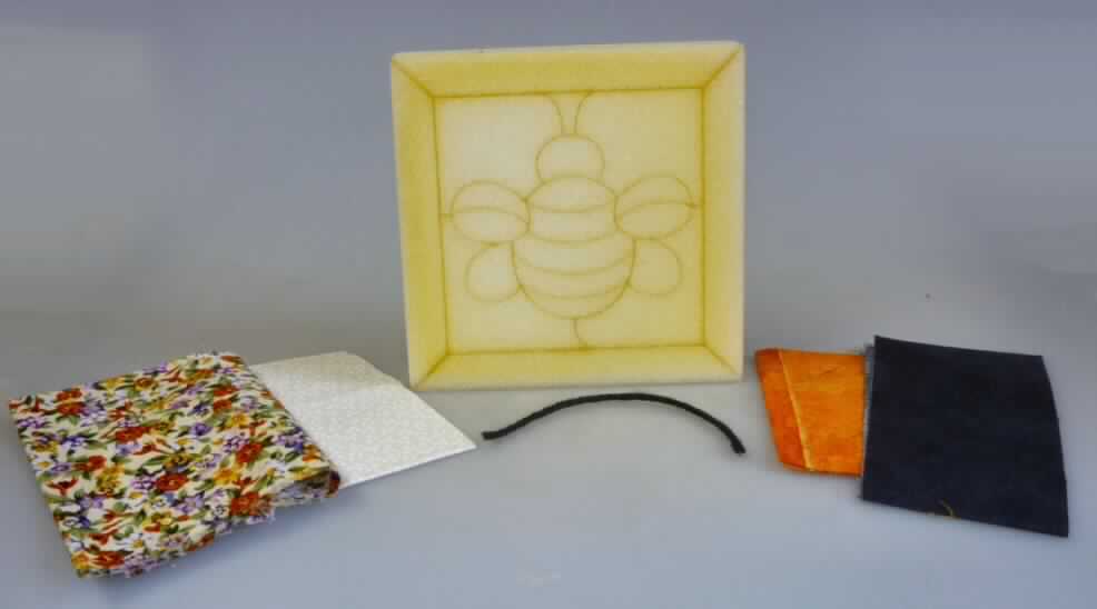 Warenzusammenstellung, bestehend aus vier Zuschnitten aus Geweben, einem Garn, einer Ware aus
Kunststoff (Kunststoff-Korpus) und zwei Drucken (Bastelanleitungen), sog. Quilt-Bastelpackung,
# 530 BumbleBee, Fotos siehe Anlage,
- in gemeinsamer Aufmachung für den Einzelverkauf in einem Polybeutel zur Ausübung einer bestimmten
  Tätigkeit (Herstellen eines Bildes, sog. Quilt, in der Art von Patchwork-Technik) zusammengestellt,
- Gewebe aus Baumwolle; in verschiedenen Abmessungen und Farben/Mustern; jeweils:
-- rechteckig zugeschnitten (nicht konfektioniert),
-- laut Untersuchungsergebnis:
--- bedruckt (anders als nach dem Batik-Verfahren handbedruckt),
--- in Leinwandbindung,
--- mit einem Quadratmetergewicht von mehr als 100g,
--- nicht auf Handwebstühlen hergestellt,
- Garn:
-- mit einer Länge von etwa 15 cm, 
-- kein Garn in Aufmachungen für den Einzelverkauf im Sinne der Anmerkung 4 zu ABS XI,
-- laut Untersuchungsergebnis:
--- aus synthetischen Spinnfasern (50 GHT Polyester und 50 GHT Polyacryl),
--- mit einer S-Drehung als letzter Drehung (u.a. deshalb kein Nähgarn der Position 5508),
- Kunststoff-Korpus:
-- quadratisch; in den Abmessungen: 14,5 cm x 14,5 cm (Seitenlänge),
-- mit einer Dicke von 2,7 cm; davon 2,5 cm aus festem Kunststoff und einer aufgeklebten Lage aus
   Schaumkunststoff mit einer Dicke von 0,2 mm;
-- in die Lage aus Schaumkunststoff sind Rillen in den Konturen einer stilisierten Hummel sowie eines
   Rahmens eingeprägt; der Kunststoff-Korpus besitzt jedoch keine eigene Zierwirkung,
- Drucke:
-- Bastelanleitung aus Pappe:
--- bildet gleichzeitig den Pappeinleger der Verpackung,
--- farbig bedruckt mit einer bildlichen Darstellung des fertigen Quilts und der einzelnen Fertigungs-
    schritte,
-- Bastelanleitung aus Papier:
--- einfarbig bedruckt mit einem Schnittmuster (Umrisse für die auszuschneidenden Gewebezuschnitte), 
- Fertigung des Quilts:
-- der größte Gewebezuschnitt bildet die Rückseite und den Rahmen,
-- aus den anderen Gewebezuschnitte werden den Konturen der Hummel und des Bild-Hintergrunds 
   entsprechende Ausschnitte zugeschnitten, deren Ränder anschließend in den vorgefertigten Ritzen
   im Schaumkunststoff gesteckt werden,
-- das Garn wird in drei Teile geschnitten, die die Fühler und den Stachel der Hummel bilden sollen,
   sie werden ebenfalls in vorgefertigte Ritzen gesteckt,
- keine Warenzusammenstellung der Position 6308, da die Gewebe ohne weitergehende Bearbeitung 
  verwendet werden,
- kein Bastelset der Position 9503 dar, da die "Bastel"-Tätigkeit lediglich im Verzieren besteht,
- insbesondere nach dem Wert bestimmen die Gewebe den Charakter der Warenzusammenstellung.

"Warenzusammenstellung
 aus Geweben (charakterbestimmend), mit einem Anteil an Baumwolle von mehr als 85 GHT und einem 
 Quadratmetergewicht von weniger als 200 g, bedruckt, in Leinwandbindung, mit einem Quadratmeter-
 gewicht von mehr als 100 g, nicht auf Handwebstühlen hergestellt, nicht nach dem Batik-Verfahren
 handbedruckt,
 einem Garn aus synthetischen Spinnfasern, kein Nähgarn, nicht in Aufmachung für den Einzelverkauf,
 einer anderen Ware aus Kunststoffen (Kunststoff-Korpus) als in den Position 3916 bis 3925 genannte
 und anderen Drucken (Bastelanleitungen) als in Positionen 4901 bis 4910 genannte"