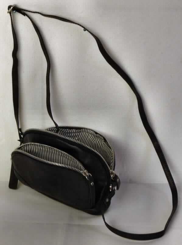 Handtasche, sog. 5th Avenue Tasche, Foto siehe Anlage, 
- mit einer Außenseite aus schwarzem Leder, 
- mit den Abmessungen von ca. 20 cm (B) x 14 cm (H) x 3 cm (T), 
- mit einem verstellbaren Schultertragegurt, 
- mit einem gefütterten Vorfach mit Reißverschluss ausgestattet,
- innen mit einem Hauptfach; am oberen Rand mit einem Reißverschluss vollständig zu schließen,
- mit einem eingesetzten Reißverschlussfach, ansonsten ohne weitere Einteilung oder Ausstattung,
- gefüttert, 
- Handtasche, da in erster Linie dazu bestimmt, kleinere persönliche Gegenstände aufzunehmen,
- keine Hinweise auf Handarbeit.

"Handtasche, mit einer Außenseite aus Leder, nicht handgearbeitet"