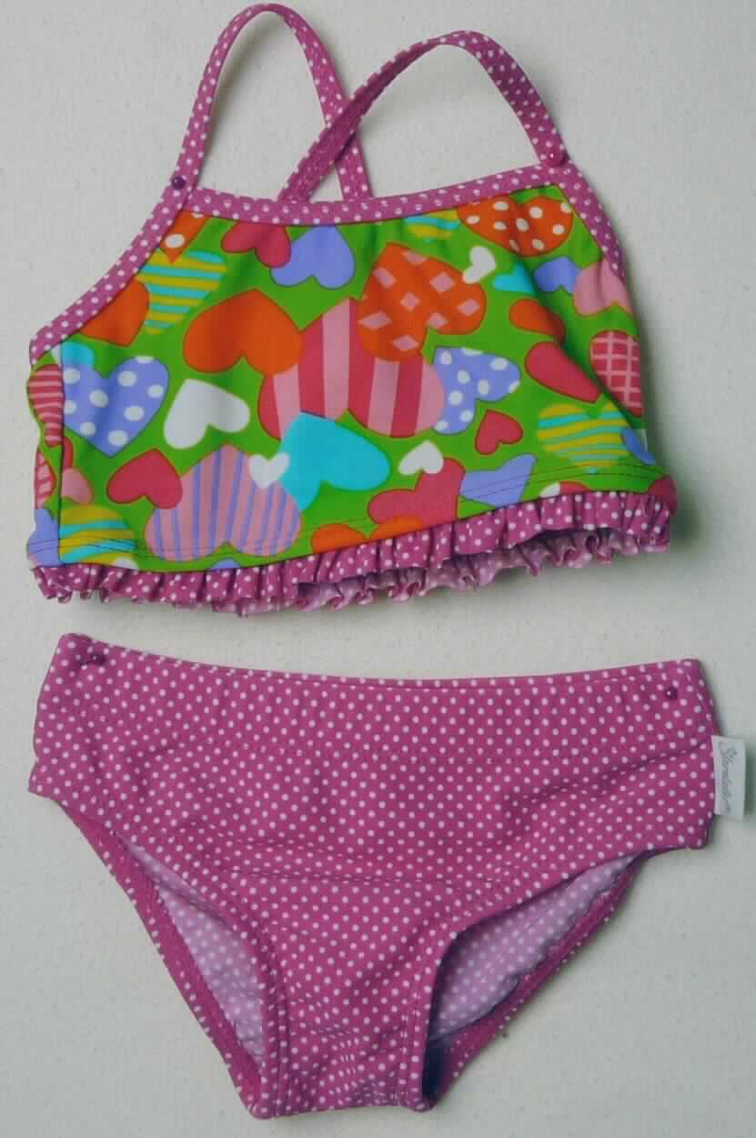 Kleidung für Kleinkinder, sog. Bikini, Art. 75381, Größen 74, 80 und 86, Foto siehe Anlage, 
- auf einem Bügel aufgemacht, 
- als zweiteiliger Badeanzug (sog. Bikini) gearbeitet,
- aus verschiedenen, ca. 0,6 mm dicken, buntbedruckten, elastischen Gewirken aus laut Antrag 82 % Polyamid und 
  18 % Elasthan (Elastomergarn, beides synthetische Chemiefasern), 
- wird aufgrund der Abmessungen als Bekleidung für Kleinkinder von der Position 6111 erfasst (somit keine Ware 
  der Position 6112), 
- Oberteil: 
-- mit Trägern, die sich im Rückenteil überkreuzen,
-- die Brust bedeckend,
-- ohne Öffnung und ohne Verschluss,
-- mit einem elastischen Abschluss am unteren Rand,
- Unterteil:
-- als Badehose gearbeitet,
-- in der Taille abschließend, mit elastischem Taillenbund, 
-- im Vorderteil leicht gefüttert, 
-- mit hohen Beinausschnitten mit elastischen Abschlüssen.

"Kleidung für Kleinkinder, aus Gewirken aus synthetischen Chemiefasern"