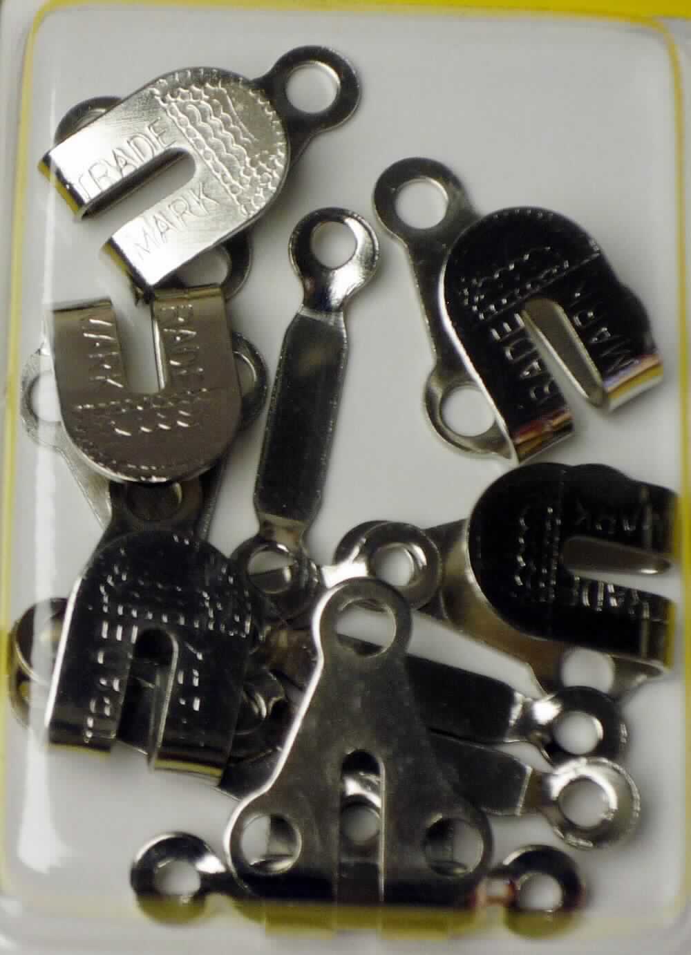 Es handelt sich um aus unedlem Metall gefertigte Haken, deren dreieckige, flache Unterseite drei kreisrunde Befestigungslochungen aufweist, und um aus unedlem Metall gefertigte, längliche Erzeugnisse (Ösen), deren Enden leicht nach unten versetzt und mit je einer kreisrunden Befestigunglochung versehen sind.
Die aufeinander abgestimmten Waren werden an Kleidung (Hosen und Röcken) verwendet. 
Jeweils sechs Haken und Ösen befinden sich in einer Sichtverpackung aus einem bedruckten Papprücken mit   
Vorderteil aus transparentem Kunststoff.
- Antragstellerangaben -

Abbildung siehe Anlage.

Derartige Erzeugnisse gehören als "Haken und Ösen aus unedlen Metallen, für Kleidung" zum TARIC-Code 8308 1000 00.