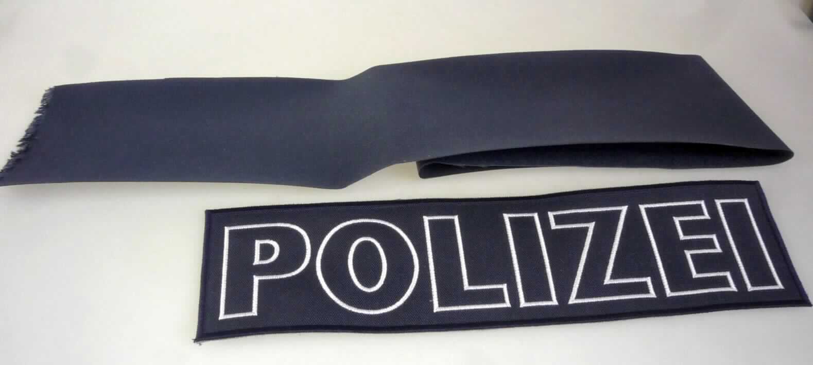 Stickerei, sog. Etikett, Foto siehe Anlage,
- rechteckig, mit den Abmessungen (L x B): 26,5 cm x 7,0 cm ,
- auf einem zweilagigen Stickgrund:
-- mit einer die Schauseite bildenden Außenlage aus einem ca. 0,4 mm dicken, einfarbigen Gewebe 
   aus laut Antrag synthetischen Chemiefasern, das auf der Unterseite mit Kunststoff (laut Antrag: Polyurethan) 
   beschichtet ist und 
-- einer der Verstärkung dienenden Unterlage aus Vliesstoff aus synthetischen Chemiefasern (laut Antrag: 
   Polyester),
- mit Stickgarnen bestickt,
- keine Ätzstickerei oder Stickerei mit herausgeschnittenem Grund,
- laut Antrag mit einem Wert von weniger als 17,50 EUR je kg Eigengewicht,
- ohne Hinweise auf Handarbeit.

"Stickerei als Motiv, andere als Ätzstickereien und Stickereien mit herausgeschnittenem Grund, aus Chemiefasern, 
 mit einem Wert von weniger als 17,50 EUR je kg Eigengewicht, nicht handgearbeitet"