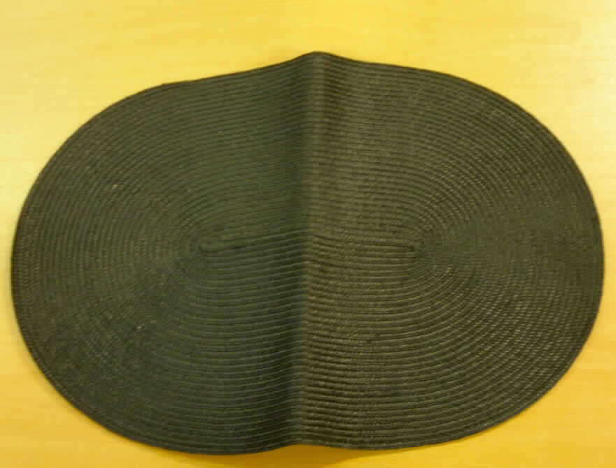 Andere Ware zur Innenausstattung, sog. Tischset "Kir", Foto siehe Anlage,
- aus einem flachen Geflecht der Position 5808 aus ca. 1 mm breiten Streifen aus synthetischer Spinnmasse
  (laut Antrag aus Polypropylen); aufgrund der Streifenbreite von weniger als 5 mm keine Ware des Kapitels 39,
- oval, laut Antrag in den Abmessungen: 45 cm x 33 cm,
- spiralförmig zusammengenäht (konfektioniert),
- wird insbesondere wegen der Art des Geflechts und der Steifheit des Materials üblicherweise nicht
  gewaschen und kennzeichnet sich aufgrund des Verwendungszwecks und der Ausstattung als Ware zur
  Innenausstattung (somit keine Tischwäsche der Position 6302).
 
"Andere Ware zur Innenausstattung (Tischset), aus Spinnstoffen, keine Ware der Position 9404, aus einem
 Geflecht aus Streifen aus synthetischer Spinnmasse"