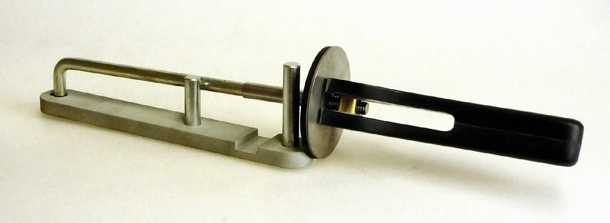 Sog. Preloader; es handelt sich um ein Haltewerkzeug für Werkstücke (Fußprothesen) zum Handbetrieb, im Wesentlichen bestehend aus

- einer Grundplatte (Länge: ca. 19 cm) mit zwei daran 
  fest angebrachten runden Haltestiften und einer Einkerbung im vorderen Bereich, vollständig aus unedlem Metall 

- sowie einem, am anderen Ende befestigten, schwenkbaren Arm aus unedlem Metall
  
-- mit einem Außengewinde versehen, an dem ein frei beweglicher Handgriff aus Kunststoff
   aufgeschraubt ist und

-- einer runden Scheibe mit einer Hülse aus unedlem Metall, die entlang des Arms nach oben und
   unten geschoben werden kann und an der Kontaktstelle zum Werkstück aus Kunststoff besteht

Das Erzeugnis dient dazu, den Ein- und Ausbau einer ansonsten schwer zugänglichen Vorfußfeder an einer Fußprothese durch Fixierung zu ermöglichen und ist in einem Kunststoffbeutel mit Pappreiter für den Einzelverkauf aufgemacht.
-Antragstellerangaben-

Abbildung siehe Anlage.

Derartige Erzeugnisse gehören als "Schraubstöcke, Schraubzwingen und dergleichen, mit arbeitendem Teil aus unedlem Metall" zur Codenummer 8205 7000 00 0 des Zolltarifs (ZT).