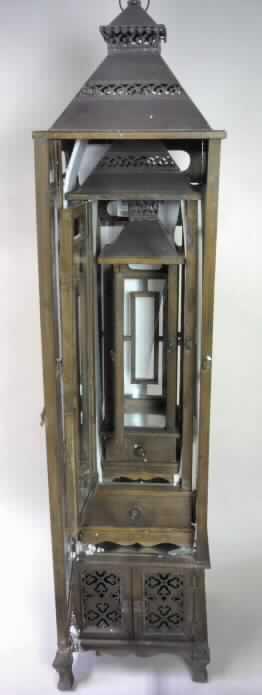 Laternenset aus Holz, 3 tlg., Art. 896043 (Unterartikel 896044, 896045, 896046) - s. Foto-, im Wesentlichen bestehend aus einem braunen Holzgestell mit Standsockel. Der obere Teil besteht aus einer rundum verglasten Laterne mit verschließbarer Tür, einer innen mit einer Platte aus unedlem Metall ausgestatteten glatten Stellfläche zur Aufnahme und zum Abbrennen von Kerzen (nicht Gegenstand dieser vZTA) und einem quadratischen Pyramidendach aus unedlem Metall, wobei der oberste Teil (und bei zwei Laternen zusätzlich auch der mittlere Teil) durchbrochen und mit einem weiteren kleinen Dach versehen ist. Im unterem Teil befindet sich eine Schublade bzw. ein mit zwei Türen ausgestatteter Schrank.

Charakterbestimmend im Hinblick auf den Umfang und die Verwendung bei der zusammengesetzten Ware ist die Laterne.

Die Ware ist als dreiteiliges Set verpackt in einem Karton. Die einzelnen Waren haben folgende Abmessungen: 37 x 37 x 160 cm (Unterartikel 896044), 28 x 28 x 110 cm (Unterartikel 896045) und 18,5 x 18,5 x 75 cm (Unterartikel 896046).

Diese Ware ist als "Nichtelektrischer Beleuchtungskörper, anderweit weder genannt noch inbegriffen, handgearbeitet" einzureihen.