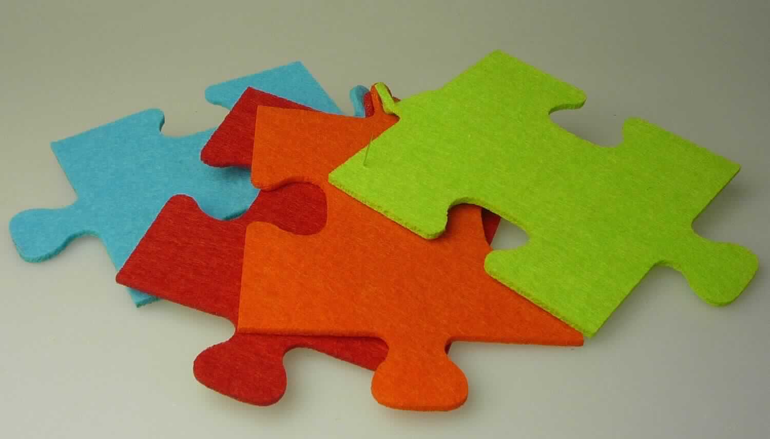 Untersetzer, sog. Untersetzer "Puzzle", Foto siehe Anlage,
- als 4er Set in verschiedenen Farben,
- in Form von Puzzleteilen gearbeitet (somit konfektioniert); laut Antrag in den Abmessungen von 10 cm x 15 cm,
- aus einem ca. 3 mm dicken, laut Untersuchungsergebnis genadelten und mit Bindemittel bzw. Bindefasern 
  verfestigten Vliesstoff aus synthetischen Chemiefasern, 
- soll als Untersetzer bei Tisch verwendet werden; wird insbesondere wegen des Materials üblicherweise nicht 
  gewaschen und kennzeichnet sich aufgrund des Verwendungszwecks und der Ausstattung als Ware zur 
  Innenausstattung, somit keine Tischwäsche der Position 6302 und auch keine Ware der Position 6307.

"Andere Ware zur Innenausstattung (Untersetzer), aus Spinnstoffen, keine Ware der Position 9404, aus
 Vliesstoffen, aus synthetischen Chemiefasern"