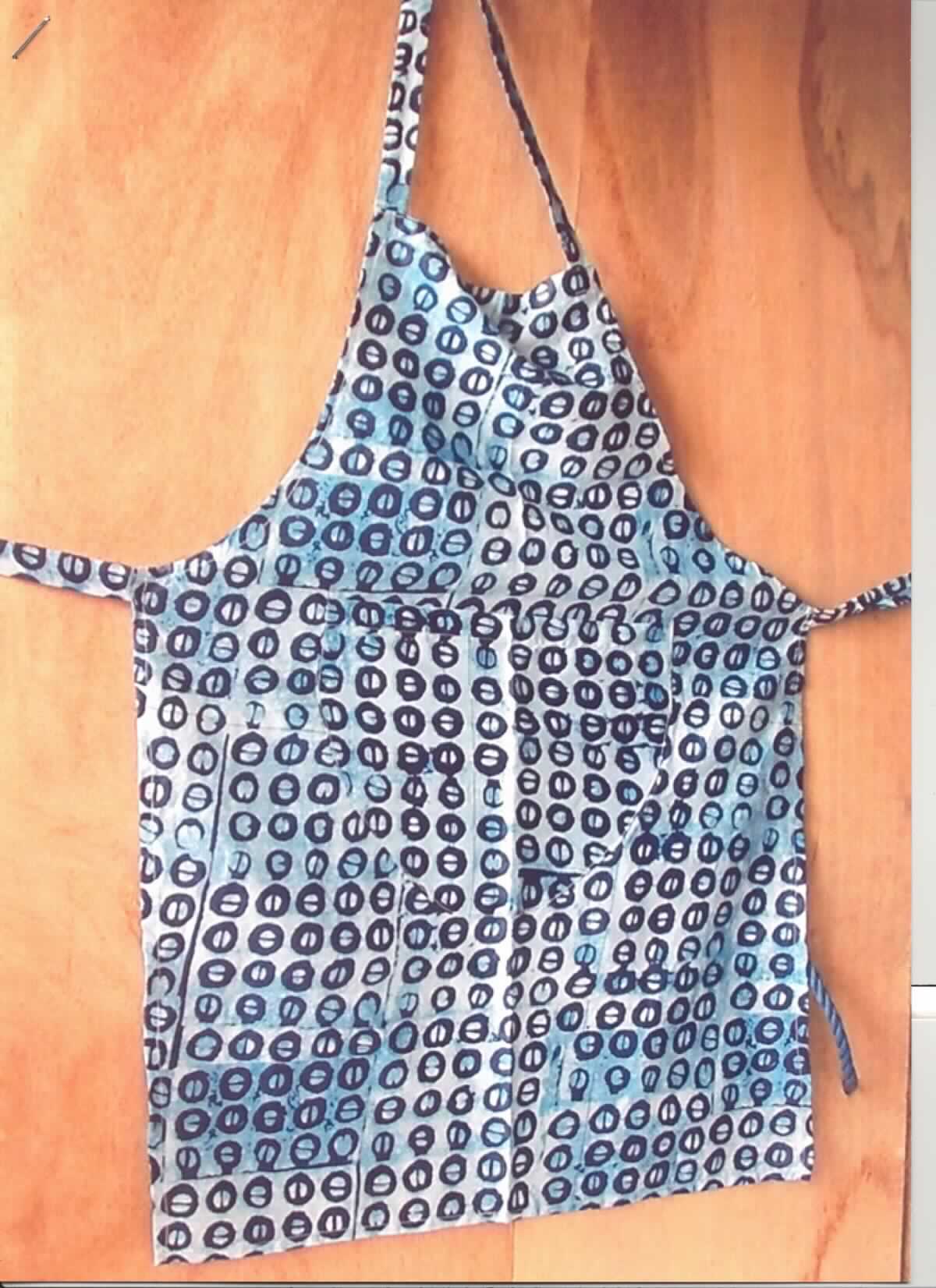 Schürze, sog. Küchenschürze, Foto siehe Anlage,
- aus ca. 0,2 mm dicken, bedruckten Geweben aus laut Antrag 100 % Baumwolle, 
- als Latzschürze gearbeitet; mit den Abmessungen von ca. 77 cm x 55 cm,
- den vorderen Teil des Körpers bedeckend,
- mit Nackenträgern und Bindebändern im Bereich der Taille,
- ohne Hinweise auf den Trägerkreis (unisex), 
- vorn mit einer aufgesetzten, offenen Tasche unterhalb der Taille,
- an allen Rändern durch Umschlagen und Festnähen gesäumt,
- lässt erkennen, dass sie dazu bestimmt ist, ausschließlich oder hauptsächlich zum (körperlichen oder 
  hygienischen) Schutz anderer Kleidungsstücke und/oder Personen bei Ausübung einer Gewerbe-, Berufs- 
  oder Haushaltstätigkeit getragen zu werden.

"Andere Kleidung (Schürze), aus Geweben, für Frauen, aus Baumwolle"