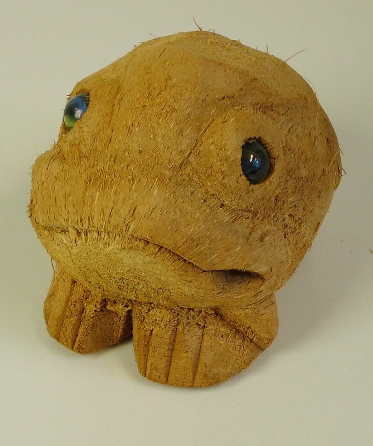 Bei der als "Kokosnuss Frosch" bezeichneten Ware handelt es sich um eine aus verschiedenen Stoffen zusammengesetzte Ware in Form eines Frosches, bestehend aus einem aus der Fruchthülle einer Kokosnuss handgefertigten Grundkörper und zwei als Augen eingesetzten Kugeln aus Kunststoff. 

Das Erzeugnis wird auch in anderen Formen, wie z.B. Affe, Schildkröte, Elefant, Hase usw. hergestellt und eignet sich als Dekoration für den Innen- und Außenbereich. Die Abmessungen ergeben sich aus den natürlichen Größen von Kokosnüssen und liegen bei 15 cm bis 25 cm.

Der hergestellte Körper aus der Fruchthülle der Kokosnuss bestimmt im Hinblick auf den Umfang und die Bedeutung für die Verwendung den Charakter der Ware.

Das Erzeugnis ist als "Ware aus pflanzlichen Schnitzstoffen, handgearbeitet" einzureihen.