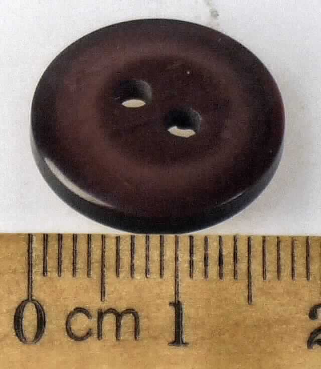 Knopf, aus Kunststoff.
Es handelt um einen Knopf aus dunkelrotem Kunststoff. Der flache Knopf ist rund (Maße:
ca. 18 x 2 mm = (Durchm. x Dicke) und mit zwei mittigen Löchern versehen.
Der Knopf kann aufgrund seiner objektiven Beschaffenheitsmerkmale als Verschluss oder als Verzierung von Bekleidungsstücken, Haushaltswäsche usw. verwendet werden. 

Die Ware ist als "Knopf, kein Druckknopf oder Teil davon, aus Kunststoff, nicht mit Spinnstoffen überzogen" einzureihen.