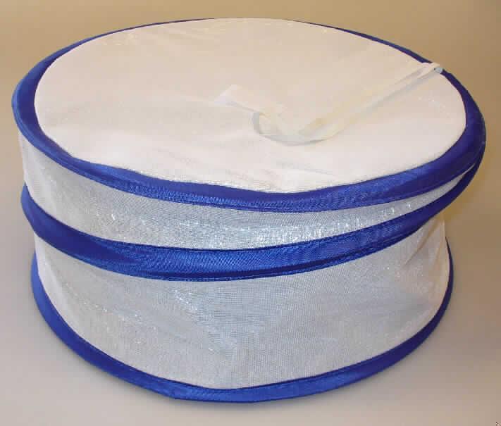 Bei dem durch ein Warenmuster veranschaulichten Artikel handelt es sich um eine zusammengesetzte Ware in Form einer so genannten "Kühl-Abdeckhaube". Das zylinderförmige, unten offene Erzeugnis mit einem Durchmesser von  ca. 41,00 cm und einer Höhe von etwa 20,00 cm besteht aus:

- einer Innenlage aus einer dicken Isolierschicht aus Schaumkunststoff, die mit einer 
  metallbedampften Kunststofffolie beklebt ist (beides Kunststoffe im Sinne der Anmerkung 
  1 zu Kapitel 39) und   
- einer Außenlage aus einem einfarbigen, dünnen, konfektionierten Kettengewirke, welches
  sich zum einen durch eine angenähte gummielastische Schlaufe und zum anderen durch 
  einen in Gewebe eingefassten spiralförmigen Metalldraht auszeichnet.

Beim Lösen des Gummi-Bandes springt der Draht im Pop-Up-Effekt nach oben und ermöglicht einen aufrechten Stand der Haube. 

Das Erzeugnis wird gewöhnlich im Haushalt als Isolierelement auf z. Bsp. Kaffeetafeln zum Schutz wärmeempfindlicher Lebensmittel wie Torten verwendet. Daher bestimmt die Kunststoffinnenlage insbesondere in Bezug auf die Verwendung  (Isolierung und Schutz vor äußeren Einflüssen) den Charakter der in einem Polybeutel aufgemachten, zusammengesetzten Ware.

Die Ware ist zolltariflich als "Artikel für den Tisch- oder Küchengebrauch, aus Kunststoffen" einzureihen.