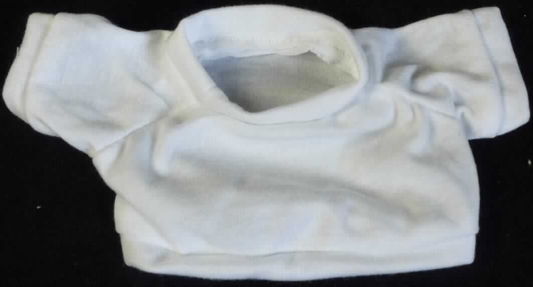 Es handelt sich um ein ca. 11 x 19,5 cm (HxB; Breite mit Ärmeln) großes, weißes T-Shirt aus Spinnstoff mit einem runden Halsausschnitt und kurzen Ärmeln. Der Kragenbereich, die Ärmelenden und der gerade, untere Rand des Shirts sind mit einem Bund ausgestattet.

Das T-Shirt ist aufgrund der Gestaltung erkennbar hauptsächlich als Zubehör für Puppen bestimmt. Eine mögliche Verwendung als Zubehör für Plüschtiere steht der Einreihung nicht entgegen. 

Die Ware dient der spielerischen Unterhaltung von Kindern mit Puppen.

Das Erzeugnis ist als "Zubehör für Puppen, nur Nachbildungen von Menschen darstellend" einzureihen.