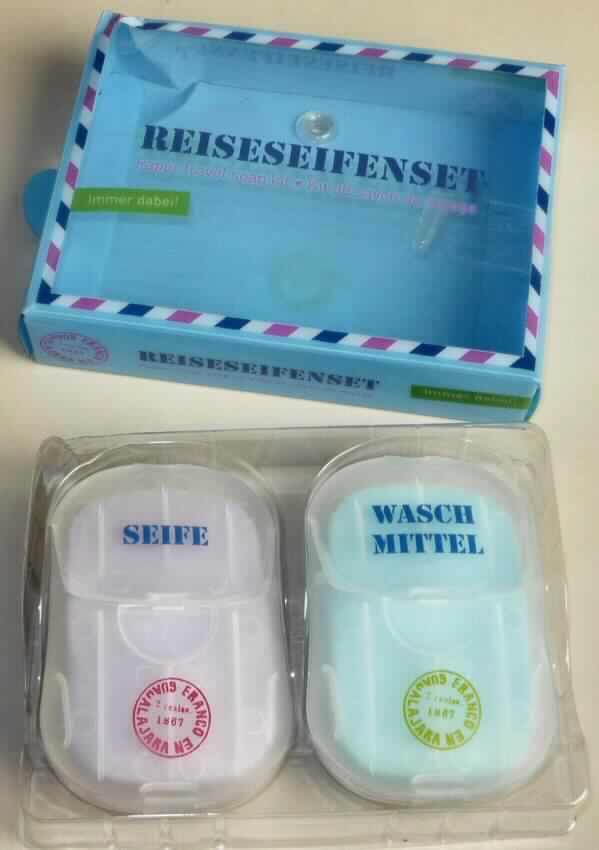 Angaben: Fernweh Reiseseifenset, Blisterverpackung mit zwei Kunststoffdöschen, gefüllt mit je 50 Stück Waschmittelblättchen bzw. Seifenblättchen; Verwendungszweck: Blättchen mit etwas Wasser aufschäumen und wie normale Seife oder Waschmittel verwenden.

Warenbeschreibung: Warenzusammenstellung zum Waschen von Händen und Textilien, gemeinsam umverpackt in einer bedruckten Blisterverpackung, bestehend aus einer wiederverschließbaren, mit "Waschmittel" beschrifteten  Kunststoffdose, gefüllt mit helltürkisfarbenen, dünnen, duftenden, mit Wasser schäumenden und sich auflösenden Blättern (Abmessungen: ca. 55 x 35 x 0,1 mm) und einer wiederverschließbaren, mit "Seife" beschrifteten  Kunststoffdose, gefüllt mit helllilafarbenen, dünnen, duftenden, mit Wasser schäumenden und sich auflösenden Blättern (Abmessungen: ca. 55 x 35 x 0,1 mm).
 
Befund: Organische, grenzflächenaktive Zubereitung (auch ohne Gehalt an Seife), als Seife verwendbar, in Form von geformten Stücken, nicht zur Körperpflege.
Da sowohl die "Seife zur Körperpflege" (Unterposition 3401 10) als auch die "andere Seife"  (Unterposition 3401 19) von gleicher Bedeutung sind, kann kein charakterbestimmender Bestandteil/Verwendungszweck nach AV 3 b) ermittelt werden und die Ware ist unter Anwendung der AV 3c) in die Unterposition 3401 19 einzureihen.