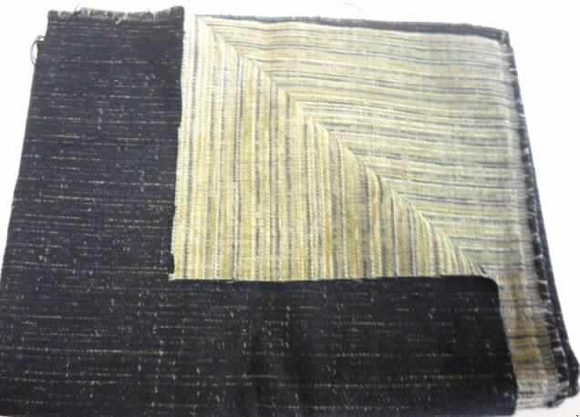 Gewebe (lt. Antrag: "Stoff Akris", siehe Foto)
- als Meterware,
- mit einer Breite von mehr als 30 cm, 
- aus (lt. Untersuchung)  28,1 GHT synthetischen Spinnfasern (7,6 GHT Polyester und 
  20,5 GHT Polyacryl), 7,9 GHT künstlichen Spinnfasern (Viskose), 30,9 GHT 
  synthetischen Filamenten (Polyester) und 33,1 GHT Baumwolle,
- mit einem Quadratmetergewicht von 394 g,
- in Musterbindung (weder Leinwand- noch Köperbindung),
- buntgewebt, 
- in größeren Abständen sind einzelne Chenillegarne eingesetzt; dadurch wird jedoch keine 
  samtartige Oberfläche erzeugt (daher kein Chenillegewebe der Position 5801).