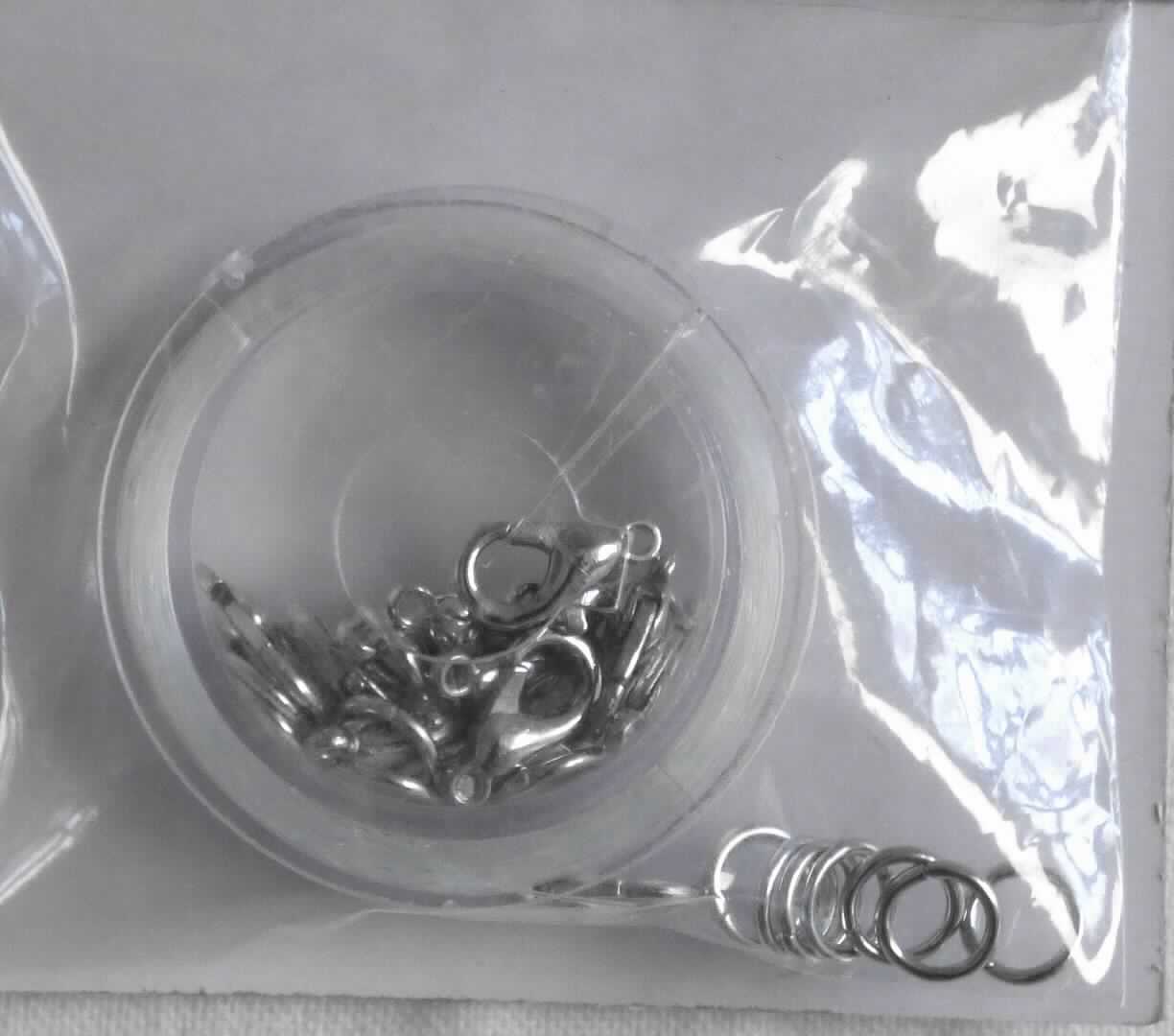 Nylonfaden mit Schließen, sog. Nylonbastelfaden mit Schließe aus Metall, Art. 14125409, Foto siehe Anlage,
- stellt sich als Warenzusammenstellung dar,
- zur Befriedigung eines speziellen Bedarfs zusammengestellt und gemeinsam in einem Polybeutel für den
  Einzelverkauf aufgemacht,
- Synthetisches Monofil:
-- als Meterware, mit einer Länge von laut Antrag ca. 20 m, auf einer Kunststoffspule aufgerollt,
-- klarsichtiges Monofil aus laut Antrag Nylon,
-- augenscheinlich mit einem Durchmesser von weniger als 1 mm und mit einem Titer von mehr als 67 dtex,
-- kein Elastomergarn,
- Schließen aus Metall:
-- 15 Stück, jeweils bestehend aus Ring und Haken aus unedlem Metall,
- insbesondere im Hinblick auf den Umfang und die Verwendung verleiht das synthetische Monofil der 
  Warenzusammenstellung ihren wesentlichen Charakter.

"Synthetisches Monofil von mehr als 67 dtex und einem größten Durchmesser von weniger als 1 mm, anderes als in 
 den Unterpositionen 5404 1100 00 bis 5404 1900 50 genannte"