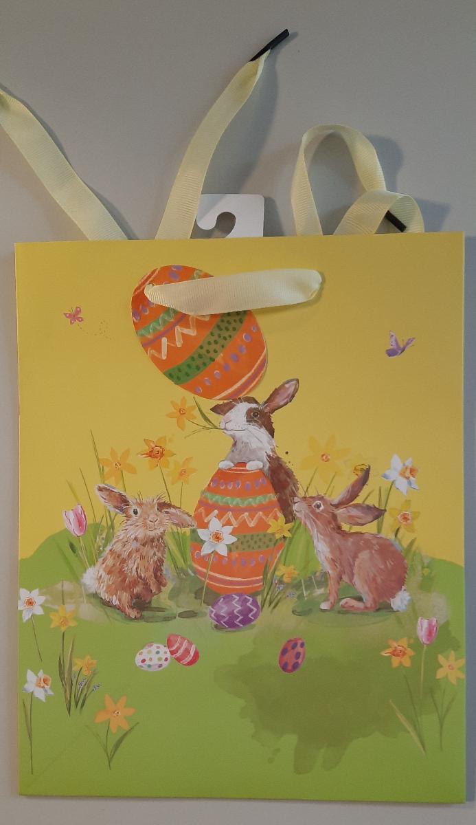 Es handelt sich um einen geklebten Blockbodenbeutel mit Seitenfalten aus mit dünner Kunststofffolie überzogenem Papier. Die Außenseiten sind mit der illustrierten Abbildung von mehreren Hasen und bunten Ostereiern auf einer Blumenwiese bedruckt. Der rechteckige Boden mit einer Breite von etwa 20 cm ist innen mit einem Pappzuschnitt verstärkt. Der obere Rand des Beutels ist nach innen eingeschlagen, an beiden Längsseiten mit Pappzuschnitten verstärkt und je Seite zweimal gelocht. Durch jedes Lochpaar ist ein als Trageschlaufe dienendes Spinnstoffband gezogen. An einem der Bänder ist ein als Geschenkanhänger zum Beschriften dienender, gelochter Zuschnitt aus einseitig oberflächengefärbtem Kartonpapier eingefädelt. Der Beutel ist auf der Innenseite am oberen Rand mittig mit einem perforierten Haken aus Pappe beklebt. 

Abbildung siehe Anlage. 

Derartige Waren gehören als "andere Säcke, Beutel oder Tüten aus Papier und Pappe, ausgenommen Schallplattenhüllen" zum TARIC-Code 4819 40 00 00, da es sich um eine aus verschiedenen Stoffen und Bestandteilen zusammengesetzte Ware handelt, deren wesentlicher Charakter nach dem Umfang sowie nach der Bedeutung für die Verwendung durch den Blockbodenbeutel aus überwiegend Papier bestimmt wird.