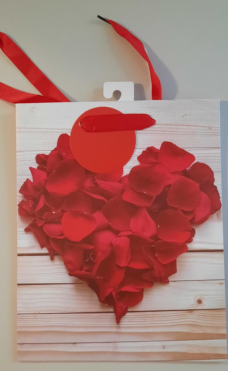 Es handelt sich um einen geklebten Blockbodenbeutel mit Seitenfalten aus mit dünner Kunststofffolie überzogenem Papier. Die Außenseiten sind mit der fotografischen Abbildung von Rosenblüten in Anordnung eines Herzens bedruckt. Der rechteckige Boden mit einer Breite von etwa 20 cm ist innen mit einem Pappzuschnitt verstärkt. Der obere Rand des Beutels ist nach innen eingeschlagen, an beiden Längsseiten mit Pappzuschnitten verstärkt und je Seite zweimal gelocht. Durch jedes Lochpaar ist ein als Trageschlaufe dienendes Spinnstoffband gezogen. An einem der Bänder ist ein als Geschenkanhänger zum Beschriften dienender, gelochter Zuschnitt aus einseitig oberflächengefärbtem Kartonpapier eingefädelt. Der Beutel ist auf der Innenseite am oberen Rand mittig mit einem perforierten Haken aus Pappe beklebt. 

Abbildung siehe Anlage. 

Derartige Waren gehören als "andere Säcke, Beutel oder Tüten aus Papier und Pappe, ausgenommen Schallplattenhüllen" zum TARIC-Code 4819 40 00 00, da es sich um eine aus verschiedenen Stoffen und Bestandteilen zusammengesetzte Waren handelt, deren wesentlicher Charakter nach dem Umfang sowie nach der Bedeutung für die Verwendung durch den Blockbodenbeutel aus überwiegend Papier bestimmt wird.
