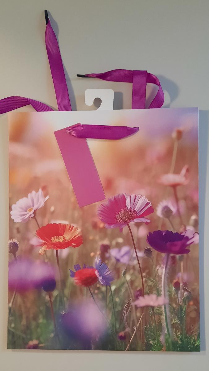 Es handelt sich um einen geklebten Blockbodenbeutel mit Seitenfalten aus mit dünner Kunststofffolie überzogenem Papier. Die Außenseiten sind mit der fotografischen Abbildung von Blumen bedruckt. Der rechteckige Boden mit einer Breite von etwa 20 cm ist innen mit einem Pappzuschnitt verstärkt. Der obere Rand des Beutels ist nach innen eingeschlagen, an beiden Längsseiten mit Pappzuschnitten verstärkt und je Seite zweimal gelocht. Durch jedes Lochpaar ist ein als Trageschlaufe dienendes Spinnstoffband gezogen. An einem der Bänder ist ein als Geschenkanhänger zum Beschriften dienender, gelochter Zuschnitt aus einseitig oberflächengefärbtem Kartonpapier eingefädelt. Der Beutel ist auf der Innenseite am oberen Rand mittig mit einem perforierten Haken aus Pappe beklebt. 

Abbildung siehe Anlage. 

Derartige Waren gehören als "andere Säcke, Beutel oder Tüten aus Papier und Pappe, ausgenommen Schallplattenhüllen" zum TARIC-Code 4819 40 00 00, da es sich um eine aus verschiedenen Stoffen und Bestandteilen zusammengesetzte Ware handelt, deren wesentlicher Charakter nach dem Umfang sowie nach der Bedeutung für die Verwendung durch den Blockbodenbeutel aus überwiegend Papier bestimmt wird.