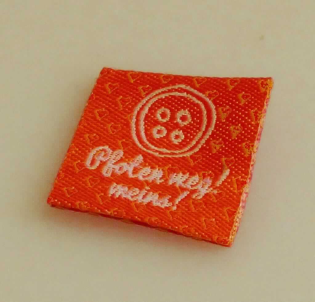 Etikett, sog. Stofflabels zum Annähen, Foto siehe Anlage,
- laut Antrag in verschiedenen Ausführungen (Formen und Größen); in einem bedruckten Pappaufhänger verpackt,
- veranschaulicht durch ein Muster mit einem Schriftzug "Pfoten weg! meins!", in den Abmessungen (L x B): 
  ca. 5 cm x 2,4 cm,
- laut Untersuchungsergebnis:
-- aus einem Jacquardgewebe aus synthetischen Chemiefasern (laut Antrag Polyester),
-- mit Kanten, die durch Heißschneiden gegen Ausriefeln gesichert sind und keine deutlichen Schmelzkanten 
   aufweisen (= nicht gesäumt / damit nicht weitergehend konfektioniert),
- mit eingewebten Inschriften und Motiven,
- nicht bestickt.

"Etikett, aus Spinnstoffen, zugeschnitten, nicht bestickt, gewebt, mit eingewebten Inschriften oder Motiven"