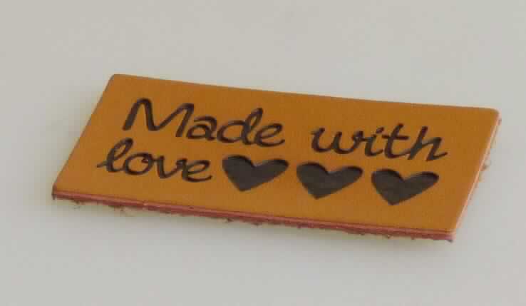 Etikett, sog. Lederlabels zum Annähen, Foto siehe Anlage,
- laut Antrag in verschiedenen Ausführungen (Formen und Größen),
- veranschaulicht durch ein Muster mit einem Schriftzug "Made with love" (rechteckig zugeschnitten); in den
  Abmessungen (L x B): ca. 4,5 cm x 2,4 cm,
- laut Untersuchungsergebnis:
-- aus einem weißen Vliesstoff aus synthetischen Chemiefasern, der auf der Außenseite (Schauseite) mit 
   bedrucktem Zellkunststoff überzogen ist; der Vliesstoff ist dicker (ca. 3/6 der Gesamtdicke) als der Zellkunststoff 
   und dient damit nicht nur der Verstärkung, 
-- auf der Rückseite mit einem Lederflock versehen,
- nicht bestickt.

"Etikett, aus Spinnstoffen, zugeschnitten, nicht bestickt, aus Vliesstoff"
