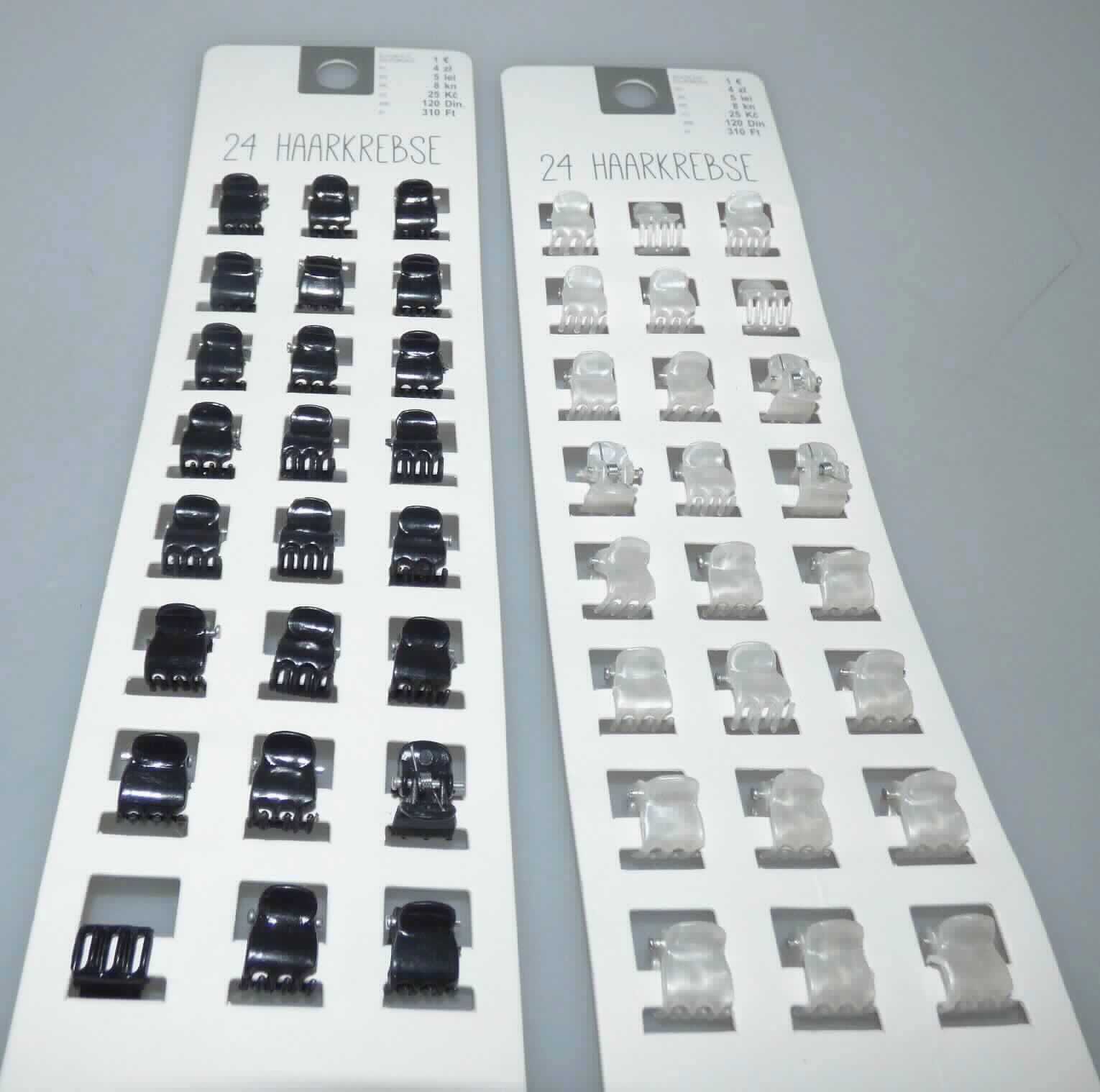 Bei den sog. "Haarklemmen, Artikel 4632200172, 6840400172" handelt es sich um 24 Haarspangen mit je einer Größe von ca. 13 x 9 x 10 mm (T x B x H) aus schwarzem oder perlmuttfarbenem Kunststoff, bestehend aus zwei zueinander gebogenen Kämmen mit jeweils drei ineinandergreifenden Zinken. Mittels eines im Griffbereich befindlichen Stiftes, auf dem eine Feder fixiert ist, werden die Kämme zusammengehalten.

Mithilfe der Feder werden die Kämme auseinandergedrückt, sodass die aufgeklappten Spangen im Haar angesetzt werden können und anschließend nach dem Zusammenklappen im Haar fixiert sind.
Die Waren bestehen aus Kunststoff (charakterbestimmendes Material insbesondere aufgrund des Umfangs), lediglich die Feder und der Stift bestehen aus unedlen Metallen.

Die Erzeugnisse dienen dem Schmücken sowie dem Zusammenhalten der Haare, sind gemeinsam auf einer bedruckten Kunststoffkarte mit Aufhängeöse für den Einzelverkauf aufgemacht und als "Haarspange, aus Kunststoff" einzureihen.