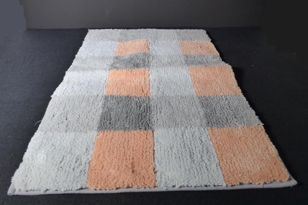 Fußbodenbelag (Badematte), sog. Chenille Badteppich Karo, Art. NAN8170714 (orange grau), 
Foto siehe Anlage,
- laut Antrag in verschiedenen Farbvarianten, 
- rechteckig, in den Abmessungen von laut Antrag 50 cm x 80 cm,
- aus synthetischen Spinnstoffen (laut Antrag 100 % Polyester),
- getuftet (Nadelflor),
- mit einem Grund aus einem Gewebe und einem nachträglich in den Grund eingezogenen Flor
  aus gezwirnten Garnen,
- an den Rändern mit schmalen Gewirkestreifen eingefasst (somit konfektioniert und u. a. 
  keine Fliese),
- auf der Rückseite rutschhemmend ausgerüstet,
- erfüllt die Bedingungen zur Einreihung als Fußbodenbelag.

"Fußbodenbelag (Badematte), aus Spinnstoffen, getuftet (Nadelflor), konfektioniert, aus 
 synthetischen Spinnstoffen (Polyester), keine Fliese"