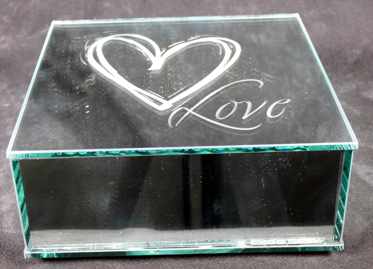 Glasware zur Innenausstattung, sog. Glas Deko mit LED "LIEBE", Foto siehe Anlage,
- aus verschiedenen Bestandteilen zusammengesetzte Ware, bestehend aus:
- einer Glasware zur Innenausstattung:
- - in Form eines hohlen Quaders,
- - aus mehreren an der Oberfläche verspiegelten (laut Antrag) manuell miteinander verklebten
    Scheiben aus gewöhnlichem Glas,
- - - der Arbeitsvorgang des manuellen Zusammenklebens stellt sich nicht als Handfertigung
       (manuelle Glasentnahme) dar,
- - an der Rückseite mit einer schwarzen Beschichtung versehen,
- - an der Vorderseite zum Teil unverspiegelt in Form eines Herzens und des Schriftzugs "Love",
- - mit den Abmessungen: ca. 15 cm (Breite) x 15 cm (Höhe) x 6 cm (Tiefe),
- einem elektrischen Beleuchtungskörper:
- - in Form einer im Inneren der Glasware lose eingelegten LED-Lichterkette mit im Dauerlicht
    leuchtenden Brennstellen,
- - mit einem in der Rückseite integrierten Batteriefach mit einem Ein-/Ausschalter,
- stellt sich insgesamt nicht als elektrischer Beleuchtungskörper der Position 9405 dar, da die Ware nicht
  der Erhellung der Umgebung dient, sondern durch die Beleuchtung lediglich die Zierwirkung der 
  Glasware erhöht wird,
- die Glasware bestimmt insbesondere nach dem äußeren Erscheinungsbild (Zierwirkung)
  den wesentlichen Charakter der zusammengesetzten Ware.

"Glasware zur Innenausstattung, aus gewöhnlichem Glas, nicht handgefertigt"