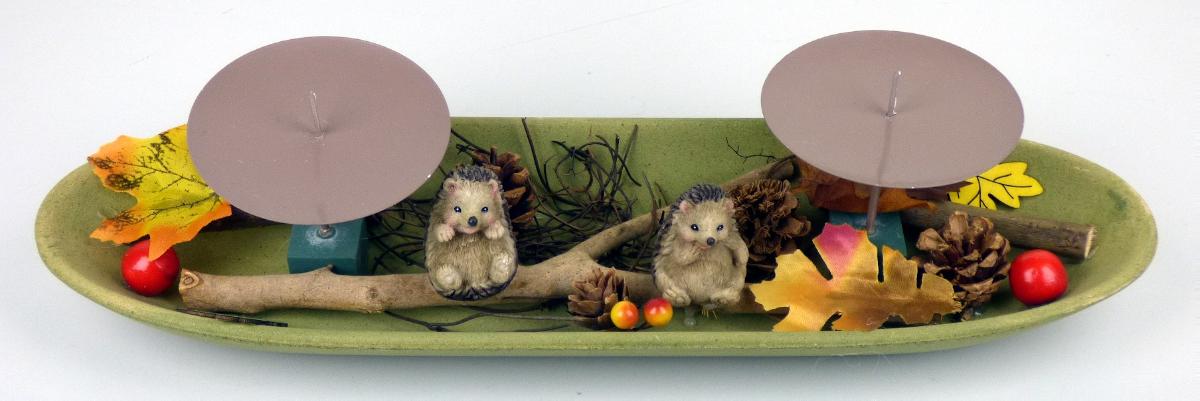 Bei dem sog. Kerzentablett, Art.-Nr. 238820 handelt es sich um einen nicht elektrischen Beleuchtungskörper, bestehend aus einer ovalen, ca. 40 cm x 11,5 cm x 4 cm (L x B x H) großen Schale aus Holz mit zwei Aufnahmevorrichtungen für Kerzen in Form einer runden Tropfschale (d: ca. 9 cm) aus Metall mit Dorn. Die Schale ist im herbstlichen Design mit diversen darauf geklebten Zierelementen (u.a. zwei stilisierte Igel, künstliche Blätter und Beeren, Tannenzapfen, einem Zweig und zwei Holzstücke) gestaltet.

Das Erzeugnis dient zu Beleuchtungszwecken und ist in einer transparenten Kunststofffolie verpackt.
Hinweise auf Handarbeit liegen nicht vor.

Die Ware ist als "nicht elektrischer Beleuchtungskörper, anderweit weder genannt noch inbegriffen, nicht handgearbeitet" einzureihen.