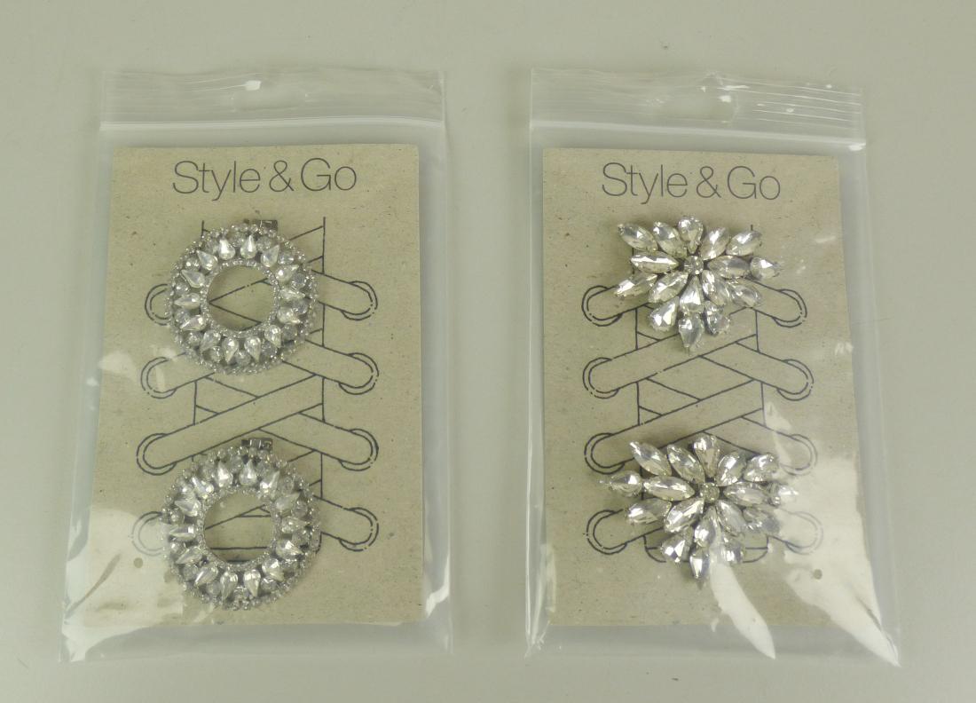 Sogenannter Schmuck für Schuhe:

Es handelt sich um aus unedlem Metall gefertigte Zierelemente für Schuhe von rund 5 cm Durchmesser. Auf einem runden, flachen Stück aus unedlem Metall sind in unedles Metall eingefasste Kunststoffsteine aufgebracht. An der Unterseite der Waren befindet sich ein Clip, mit dem das Shoe-Accessoire an Schuhbändern, Schnürsenkeln oder auch direkt an der Oberseite von Schuhen befestigt werden kann. Die Zierelemente können in der Form / Art variieren, z.B. Blumenformen oder auch Rosettenformen.
 - Antragstellerangaben -
Abbildung siehe Anlage.

Nach Umfang und Bedeutung für die Verwendung sind die unedlen Metalle charakterbestimmend (sie bestimmen die Formbgebung und dienen der Befestigung).

Eine Einreihung als Schuhteile in die Position 6406 kommt nicht in Betracht, da die Waren sich als Zier-/Schmuckwaren darstellen.

Derartige Erzeugnisse gehören als "anderer (als in den TARIC-Codes 7117 1100 00 und 7117 1900 10 genannter) Fantasieschmuck, aus unedlen Metallen" zum TARIC-Code 7117 1900 90.