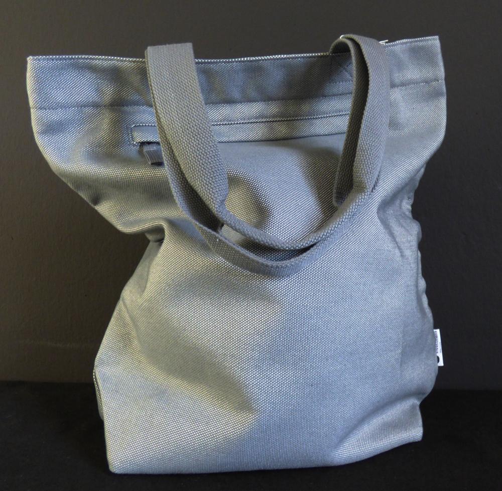 Einkaufstasche, sog. Shopper-Tasche, Foto siehe Anlage,
- vollständig aus Spinnstoffen (Gewebe aus laut Antrag Baumwolle und Polyester) gefertigt,
- mit zwei Tragegriffen,
- an der Rückseite mit einem eingesetzten Reißverschlussfach,
- das Hauptfach ist mit einem ca. 5 cm unterhalb des oberen Rands verlaufenden
  Reißverschluss versehen,
- - ungefüttert; mit einem angenähten Reißverschlussfach ausgestattet,
- mit den Abmessungen: ca. 42 cm (Breite) x 44 cm (Höhe) x 14 cm (Tiefe),
- ohne Hinweise auf Handarbeit.

"Einkaufstasche, mit Außenseite aus Spinnstoffen, nicht handgearbeitet"