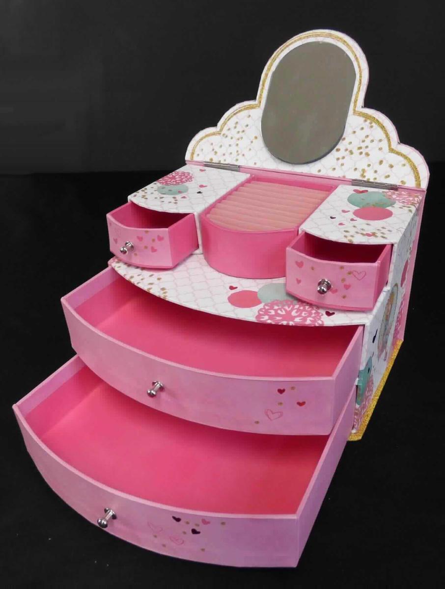 Schachtel für Schmuckwaren, sog. Schmuckkasten aus Pappe, Foto siehe Anlage,
- in Form einer Kommode in Miniaturform,
- mit einer Außenseite aus bunt bedrucktem Papier,
- - mit einer klarsichtigen Kunststofffolie überzogen; die Kunststofffolie ist als eigene Lage mit dem bloßem Auge
    nicht wahrnehmbar, teilweise mit Glitter beklebt,
- - mit einer formgebenden Unterkonstruktion aus Pappe,
- mit einem aufklappbaren Deckel mit Scharnieren aus unedlem Metall; an der Innenseite mit einem angeklebten
  Spiegel versehen,
- innen mit einer Einsteckvorrichtung für Ringe aus Spinnstoffen ausgestattet,
- mit je zwei kleinen und großen, vollständig herausziehbaren, Schubladen mit kleinen Knäufen aus unedlem Metall,
- mit einer Größe von ca. 18,5 cm (Breite) x 13 cm (Höhe) x 14 cm (Tiefe),
- zur Aufbewahrung von Schmuckwaren vorgesehen.

"Schachtel für Schmuckwaren, mit Außenseite aus Papier"