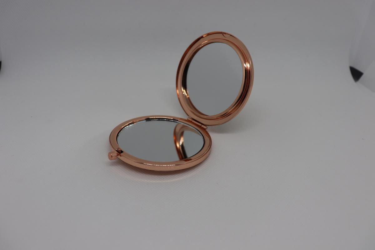 Taschenspiegel aus Glas, sog. klappbarer Taschenspiegel, Foto siehe Anlage,
- in einer runden, zweiteiligen Fassung aus unedlem Metall,
- aufklappbar, mit einem Druckknopfmechanismus,
- an der Rückseite des Deckelteils mit Pailletten versehen, die mit einer Kunststofffolie überzogen sind,
- mit einem im Deckelteil eingesetzten, runden Spiegel aus Glas,
- mit einem im Bodenteil eingesetzten, runden Spiegel aus Glas,
- mit einem Durchmesser von ca. 7 cm.

"Spiegel aus Glas (Taschenspiegel), gerahmt"