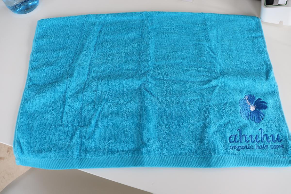 Wäsche zur Körperpflege, sog. Handtuch Baumwolle, Foto siehe Anlage,
- in zwei unterschiedlichen Varianten, jeweils in einem Polybeutel verpackt,
- Variante 1:
-- rechteckig, in den Abmessungen von ca. 49,5 cm x 31 cm,
-- aus ca. 1,9 mm dicken, buntgewebten Schlingengeweben nach Art der Frottiergewebe aus laut Antrag 
   100 % Baumwolle,
- Variante 2:
-- rechteckig, in den Abmessungen von ca. 71 cm x 52 cm,
-- aus ca. 1,9 mm dicken, einfarbigen Schlingengeweben nach Art der Frottiergewebe aus laut Antrag 
   100 % Baumwolle,
-- mit einem aufgestickten Firmenemblem versehen,
- an allen Rändern durch Umschlagen und Festnähen gesäumt (somit konfektioniert),
- mit einem Etikett mit Waschanleitung versehen,
- wird üblicherweise gewaschen,
- aufgrund der verwendeten Flächenerzeugnisse keine Ware der Unterposition 6302 93.

"Wäsche zur Körperpflege, aus Spinnstoffen, aus Frottierware aus Baumwolle, aus Geweben"