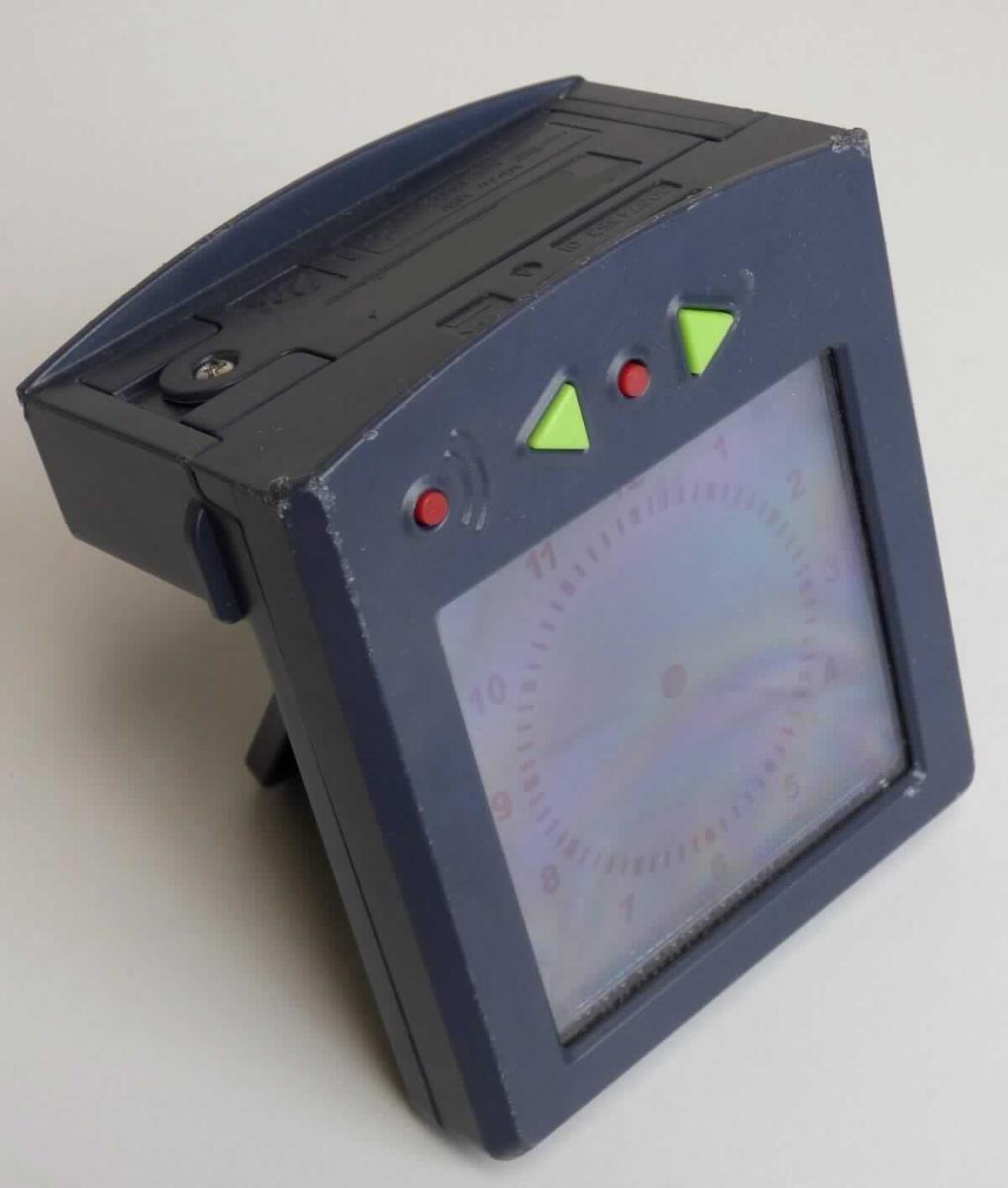 Bei der sog. "LCD-Schuluhr/Wecker" Art. 30674353 handelt es sich im Wesentlichen um einen elektrisch betriebenen Wecker. Er weist ein etwa  90 x 80 x 50 mm (B x H x D) großes Kunststoffgehäuse, mit digitaler Anzeige der Uhrzeit (Stunde, Minuten und Sekunden) auf. Oberhalb der Anzeige befinden sich vier Knöpfe, mit denen die Uhrzeit sowie eine Weckfunktion mit drei unterschiedlichen Wecktönen eingestellt werden kann, sowie ein Batteriefach mit zwei 1,5 V AAA-Batterien. Die Größe der Platine inklusive Display, die zu einem Ganzen verbunden sind, beträgt: 78 mm x 90 mm x 15 mm (B x H x D); somit liegt kein Kleinuhr-Werk i.S.d. Anmerkung 3 zu Kapitel 91 vor. 

Die Uhr findet zum einen als Teil eines Spielzeugs aus Kunststoff im Kontext eines Schulgebäudes als Schuluhr Verwendung und kann als Wecker benutzt werden.

Eine Einreihung als Spielzeug in die Position 9503 kommt nicht in Betracht, u.a. da das Erzeugnis aufgrund seiner Funktion als Uhr nicht der spielerischen Unterhaltung dient und auch als "Teil" nicht erkennbar ausschließlich oder hauptsächlich für eine Ware des Kapitels 95 bestimmt ist.

Das Erzeugnis ist als "andere als in den Positionen 9101 bis 9104 erfasste Uhr, Wecker, elektrisch betrieben" einzureihen.