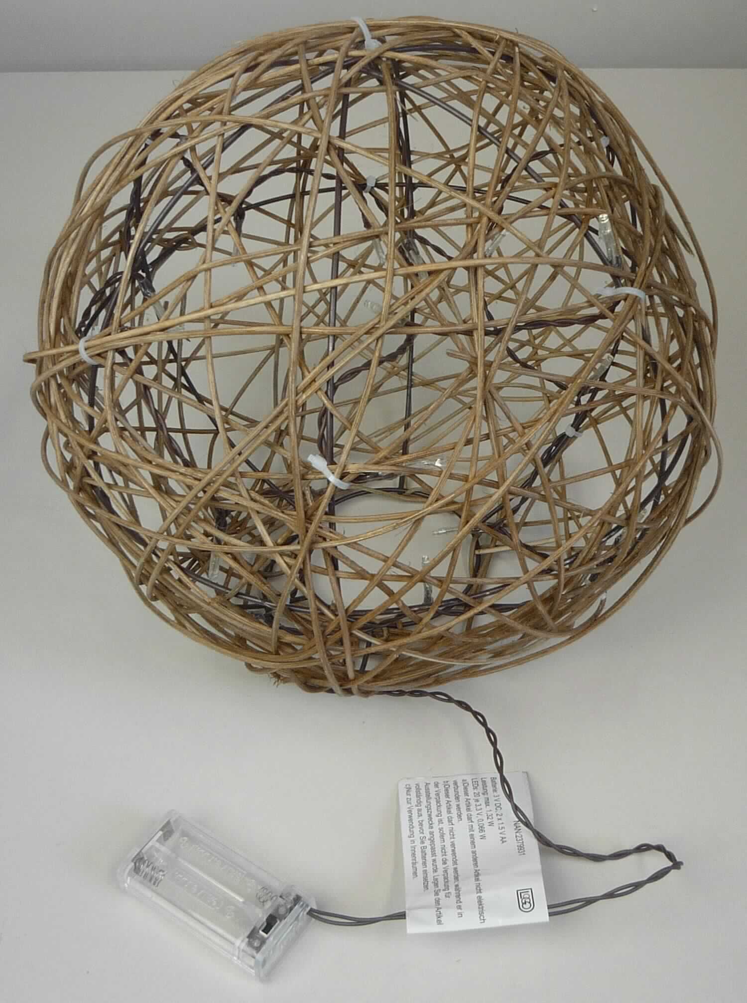 Nach den Angaben der Antragstellerin sowie dem vorliegenden Warenmuster handelt es sich bei dem Artikel 195829 um einen sogenannten Deko Ball mit 20 LED.
Das kugelförmige (Durchmesser ca. 30 cm) Erzeugnis besteht aus einem Drahtgestell, welches locker, unmittelbar mit dünnen Rattanzweigen (Flechtstoff im Sinne der Anmerkung 1 zu Kapitel 46; charakterverleihend) umflochten ist.
In die unten offene (Standfläche) Kugel ist eine batteriebetriebene Lichterkette mit 20 LED integriert.

Der Charakter der aus verschiedenen Bestandteilen zusammengesetzten Ware wird durch die Dekorationskugel bestimmt, deren Zierwirkung durch den Beleuchtungskörper lediglich erhöht wird.

Die nach den ergänzenden Angaben nicht handgearbeitete Ware ist in einem bedruckten Pappkarton verpackt.

Zolltarifrechtlich handelt es sich um "Flechtstoffwaren, unmittelbar aus pflanzlichen Flechtstoffen hergestellt, aus Rattan, nicht handgearbeitet".