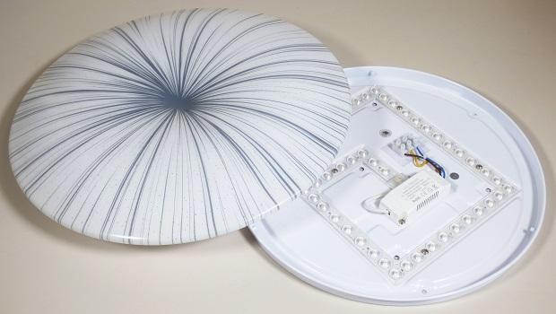 Bei der sog. "Led Ceiling Lampe, 7594086" handelt es sich um eine ca. 410 x 410 x 65 mm große, elektrische Deckenleuchte, im Wesentlichen bestehend aus einer kreisrunden, tellerförmigen Metallhalterung mit integriertem LED-Leuchtmittel (SMD LED), einer kreisförmigen, gewölbten und gemusterten (von der Mitte nach außen geführte blaue Linien in unterschiedlichen Stärken) Kunststoffabdeckung und elektrischer Ausstattung.
Die Leuchte dient zu Beleuchtungszwecken im Innenbereich und ist zur Deckenmontage bestimmt.

Der Kunststoff bestimmt nach dem äußeren Erscheinungsbild (Zierwirkung) und der Bedeutung in Bezug auf die Verwendung hinsichtlich der Lichtlenkung gegenüber dem Metall als Stabilität verleihender Bestandteil den Charakter der Leuchte.

Das Erzeugnis ist als "Leuchte, anderweit weder genannt noch inbegriffen, elektrische Deckenleuchte, ausgenommen solche von der für öffentliche Plätze oder Verkehrswege verwendeten Art, ausschließlich zur Verwendung mit LED-Lichtquellen bestimmt, aus Kunststoff, nicht für zivile Luftfahrzeuge" einzureihen.