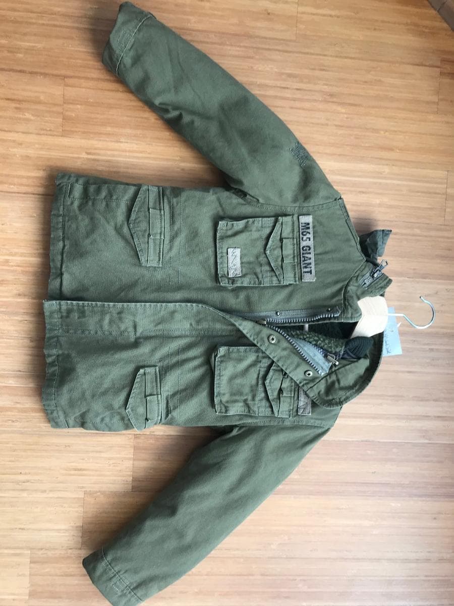 Zwei miteinander verbundene Kleidungsstücke, bestehend aus einem Anorak (Außenteil) und einem
anorakähnlichen Kleidungsstück (Innenteil), sog. M65 Giant Kids, Art. 6013, Größe 122/128, Foto
siehe Anlage,
- in einem Polybeutel verpackt,
- die Kleidungsstücke sind durch Reiß- und Druckknopfverschlüsse miteinander verbunden, können
  aber auch separat getragen werden,
- Anorakähnliches Kleidungsstück:
-- aus einem zweilagigen, durch Steppen abgeteilten Verbunderzeugnis, mit einer Außenlage aus ca.
   0,1 mm dicken, einfarbigen Geweben aus laut Antrag synthetischen Chemiefasern und einer Innenlage
   aus Wattierungsstoff,
-- durchgehend gefüttert,
-- über die Taille reichend (Rückenlänge: ca. 47 cm),
-- mit einem runden Halsausschnitt mit einer gerippt gewirkten Randeinfassung, die hinten einen
   Stehkragen bildet,
-- vorn mit einer durchgehenden Öffnung mit Reißverschluss,
-- ohne Hinweise auf den Trägerkreis (unisex),
-- mit langen Ärmeln,
-- am unteren Rand mit einem schmalen Band aus Geweben eingefasst,
-- wird im Allgemeinen über jeder anderen Kleidung und zum Schutz gegen das Wetter getragen, somit
   keine Jacke.

"Anorakähnliches Kleidungsstück, aus Geweben, für Mädchen, aus Chemiefasern"