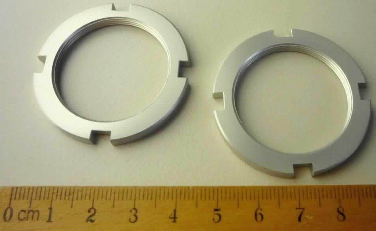 Es handelt sich um nahezu kreisrunde Muttern aus Aluminium mit Innengewinde und mit einer Lochweite von etwa 33 mm. Die Erzeugnisse weisen am äußeren Rand vier Aussparungen auf, die als Kraftansatz für einen Steckschlüsseleinsatz dienen. Die Waren dienen der lösbaren Befestigung von Bauteilen eines Elektrofahrrades.
- Antragstellerangaben -
Höhe: etwa 4 mm; Außendurchmesser: etwa 44 mm.

Abbildung siehe Anlage.

Derartige Erzeugnisse gehören als "andere Waren (Muttern) aus Aluminium" zum TARIC-Code 7616 10 00 99.