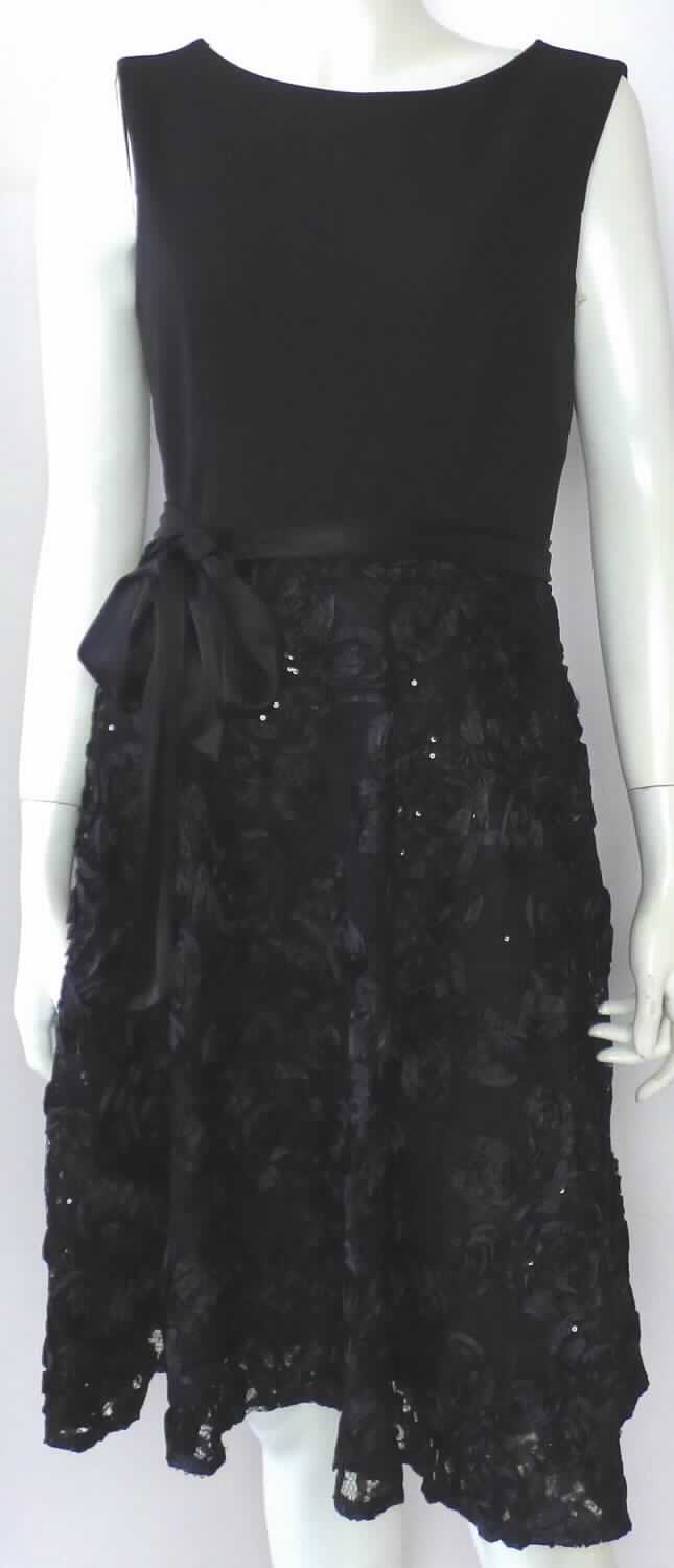 Kleid, Style 7161100215, Größe 36, Foto siehe Anlage,
- mit einem Oberteil aus ca. 0,8 mm dicken, einfarbigen Gewirken aus laut Antrag 95 % Polyester und
  5 % Elasthan (beides synthetische Chemiefasern) und einem Rockteil aus einer Applikationsstickerei
  (Pailletten aus Kunststoff und Gewebebänder) der Position 5810 mit einem Stickgrund aus einfarbigen, 
  durchbrochen gearbeiteten Gewirken aus laut Antrag 100 % Polyester,
- durchgehend gefüttert,
- über den halben Oberschenkel reichend (Rückenlänge: ca. 98 cm), 
- mit rundem Halsausschnitt,
- hinten mit einer bis in den Rockteil reichenden Öffnung mit Reißverschluss,
- ärmellos, 
- in der Taille mit hinten angenähten Bindebändern,
- am unteren Rand durch Umschlagen und Festnähen gesäumt, 
- kann ohne ein weiteres den Unterkörper bedeckendes Kleidungsstück getragen werden,
- im Hinblick auf das äußere Erscheinungsbild, den Umfang und den Wert verleihen die Stickereien der Ware
  ihren wesentlichen Charakter.

"Kleid, aus Stickereien, für Frauen, aus synthetischen Chemiefasern"